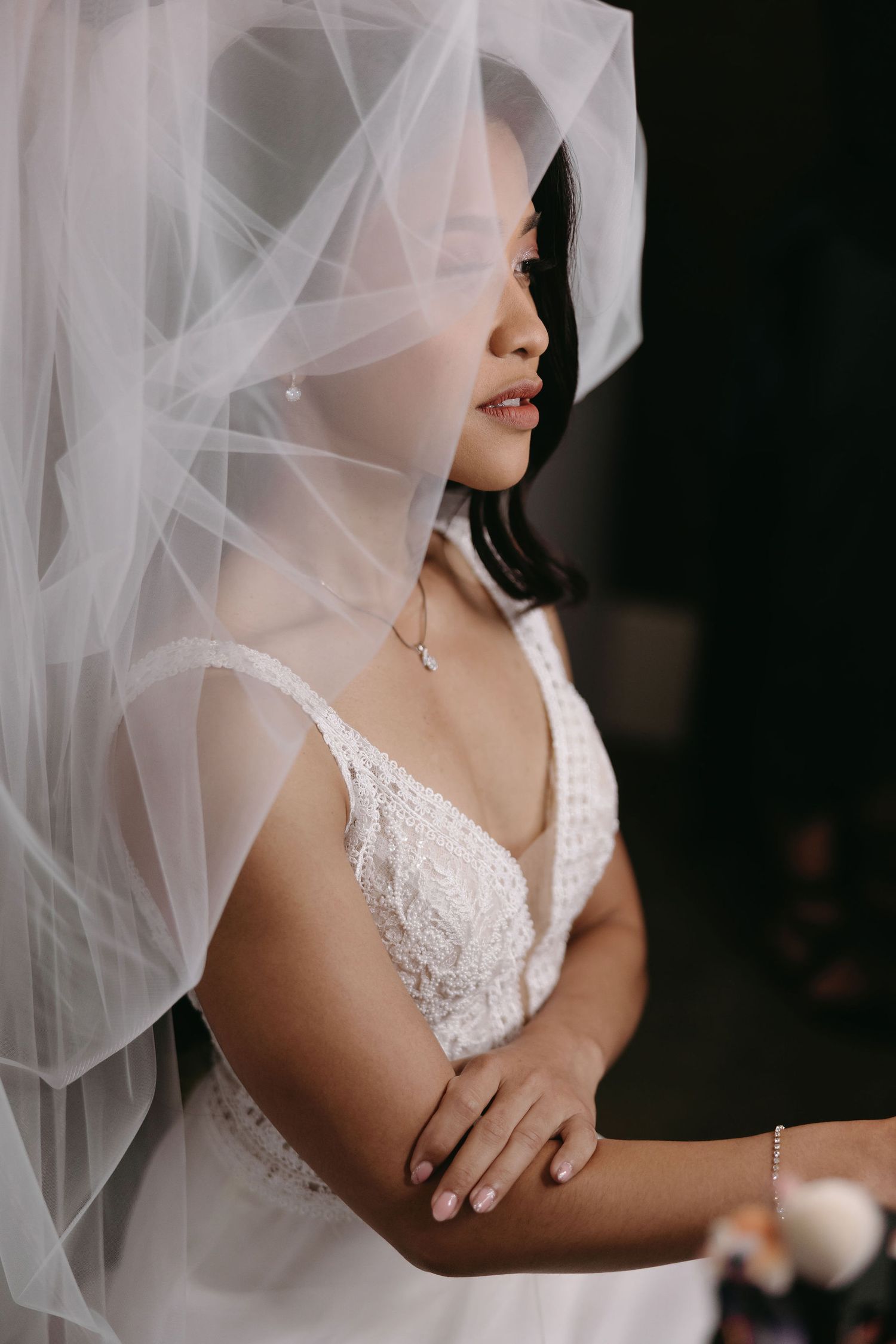 Delicate bridal portrait featuring lace details and flowing veil in ethereal lighting.