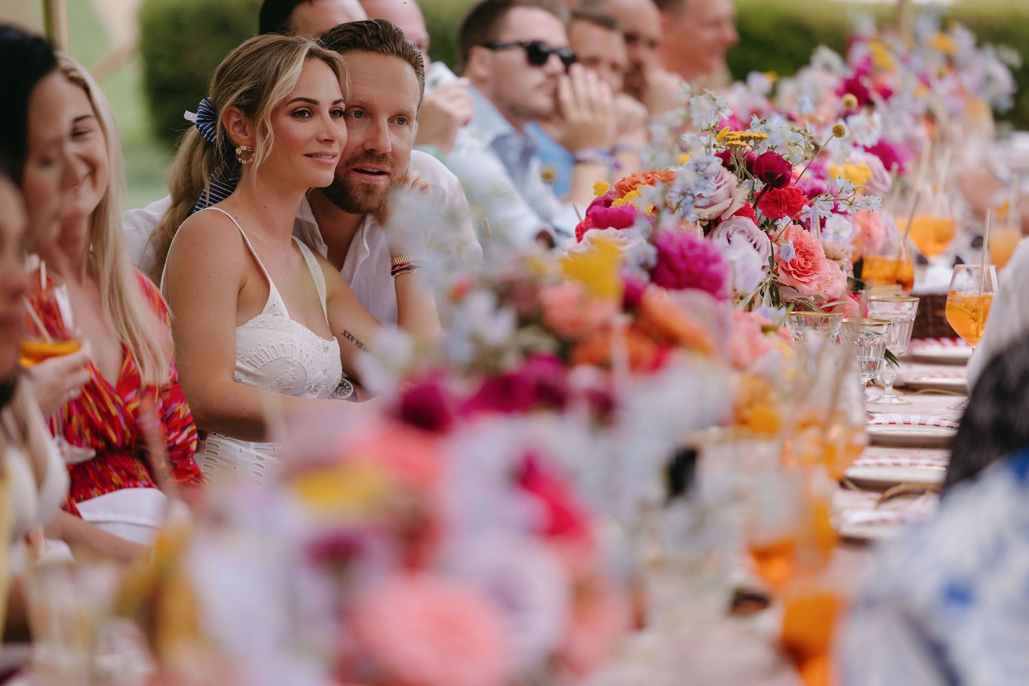 Wedding reception table decorated with vibrant pink and orange floral arrangements.