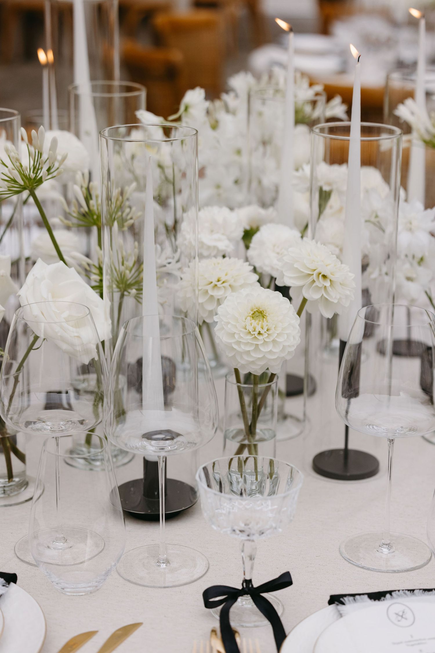Elegant wedding table setting with white flowers and crystal glassware on white tablecloth.