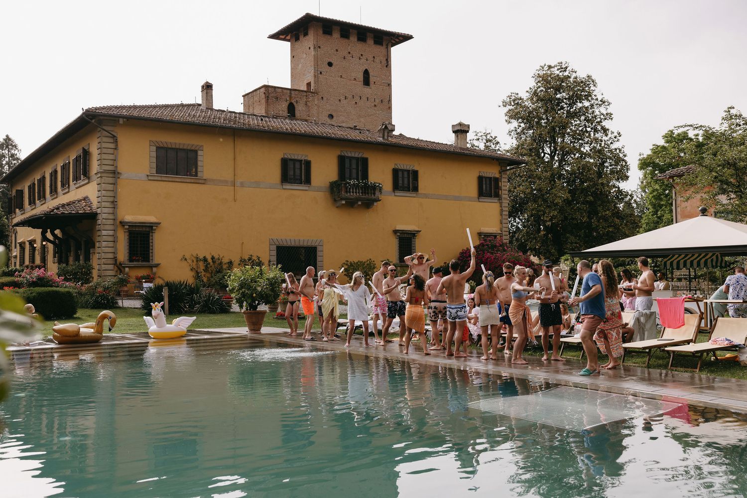 Large group gathered by a luxurious pool outside an Italian villa.