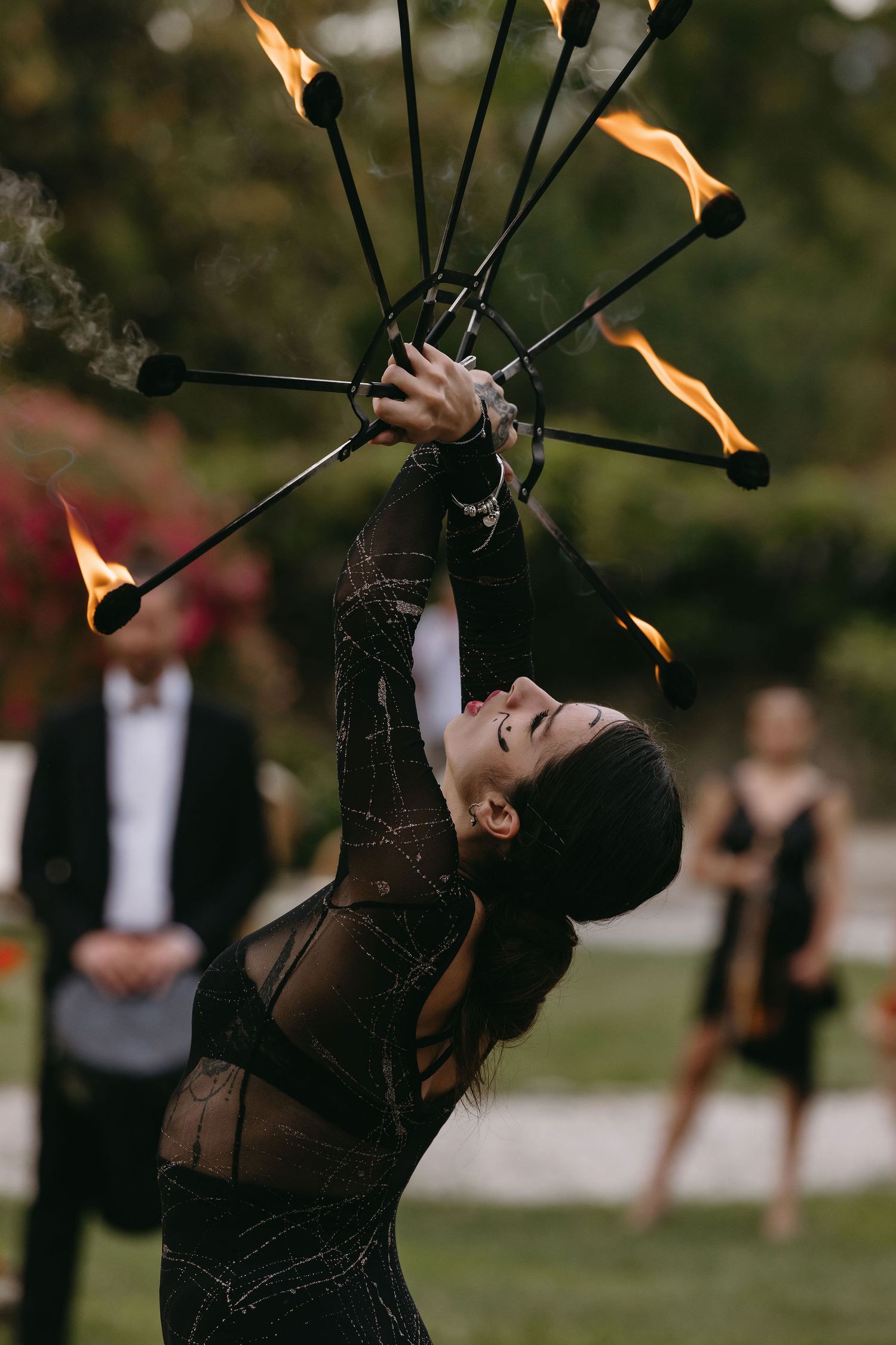 Fire performer with flaming torches entertaining guests at an outdoor event.