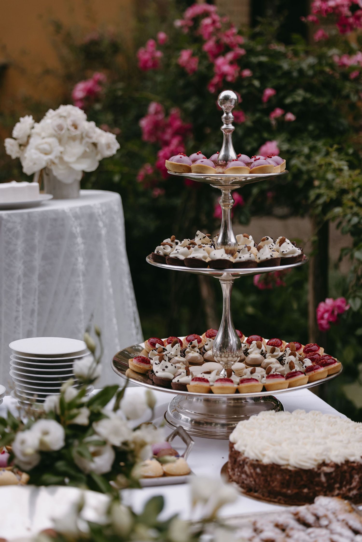 Elegant three-tiered dessert stand filled with pastries and treats at a wedding reception.