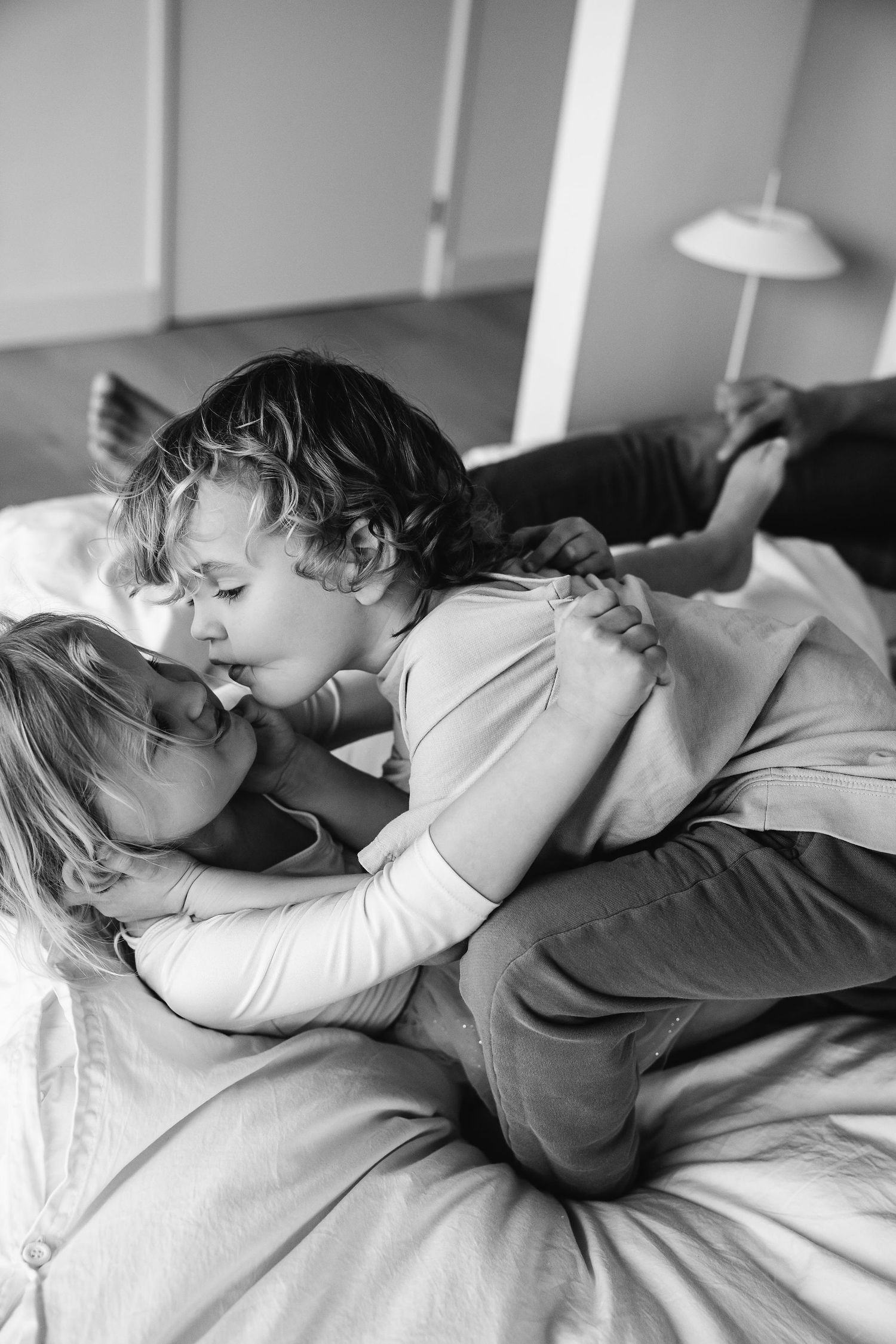 Black and white photo sequence showing tender moments of rest and connection on a bed.