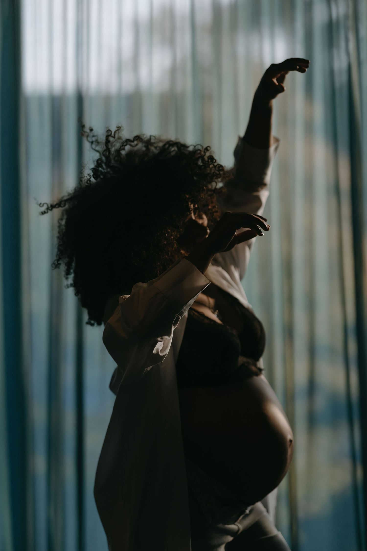 Artistic silhouette of a person with curly hair against window light.