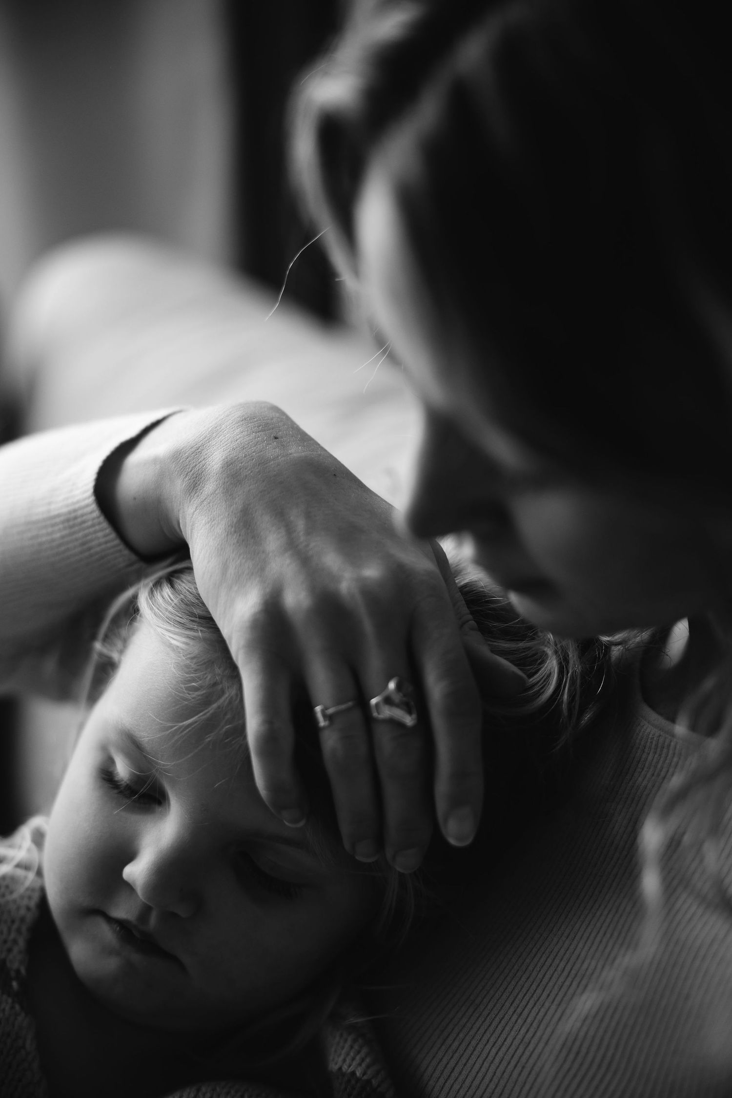 Dramatic black and white close-up capturing tender family moment in soft light.