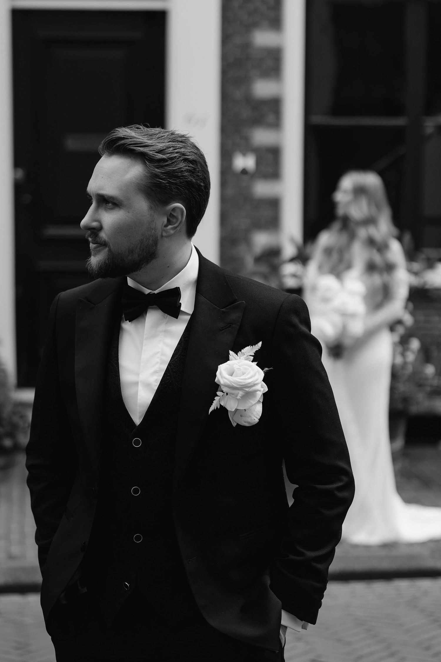 Formal black and white portrait of groom wearing tuxedo with boutonniere.