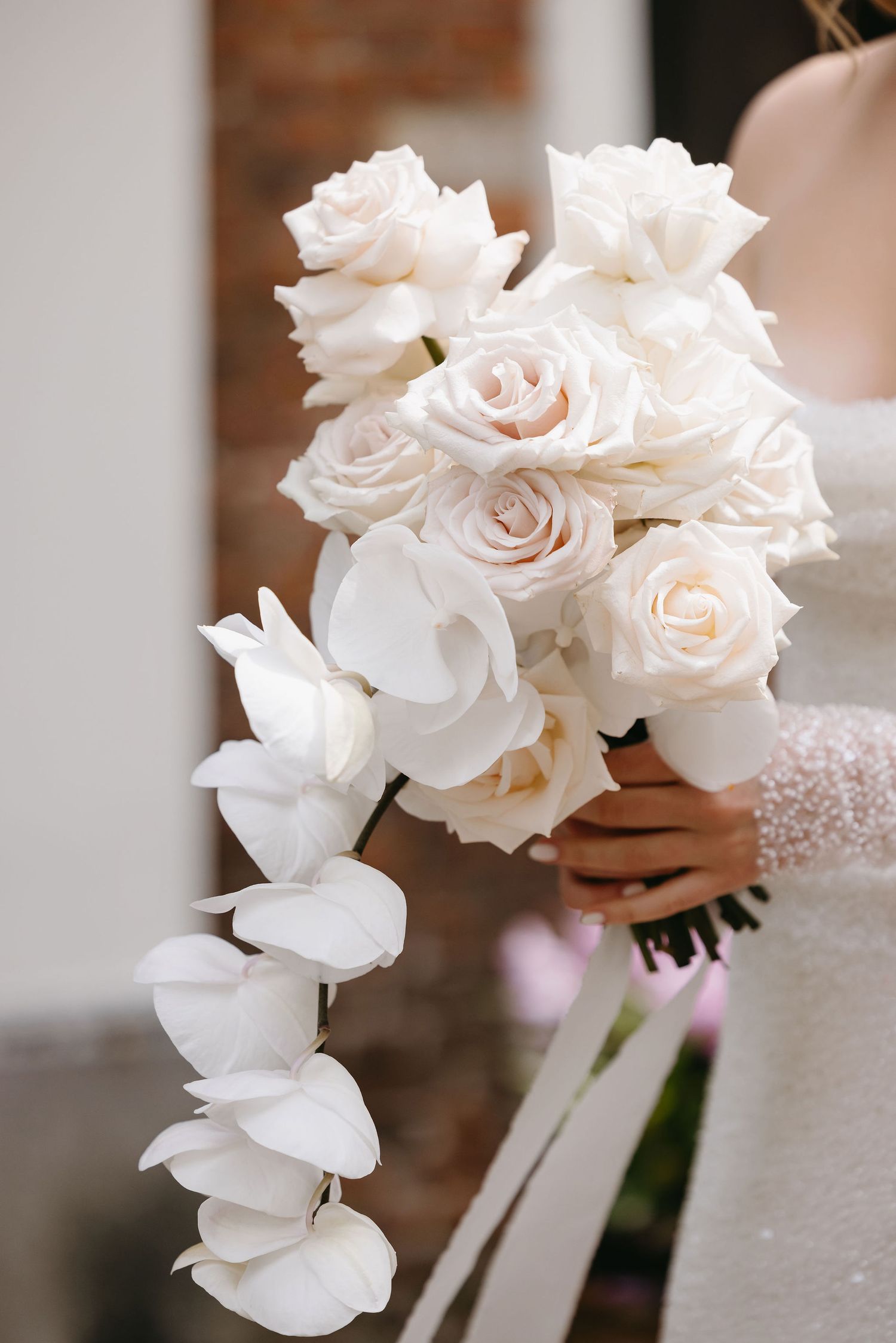 A delicate bouquet of white roses held in hands with lace sleeves.