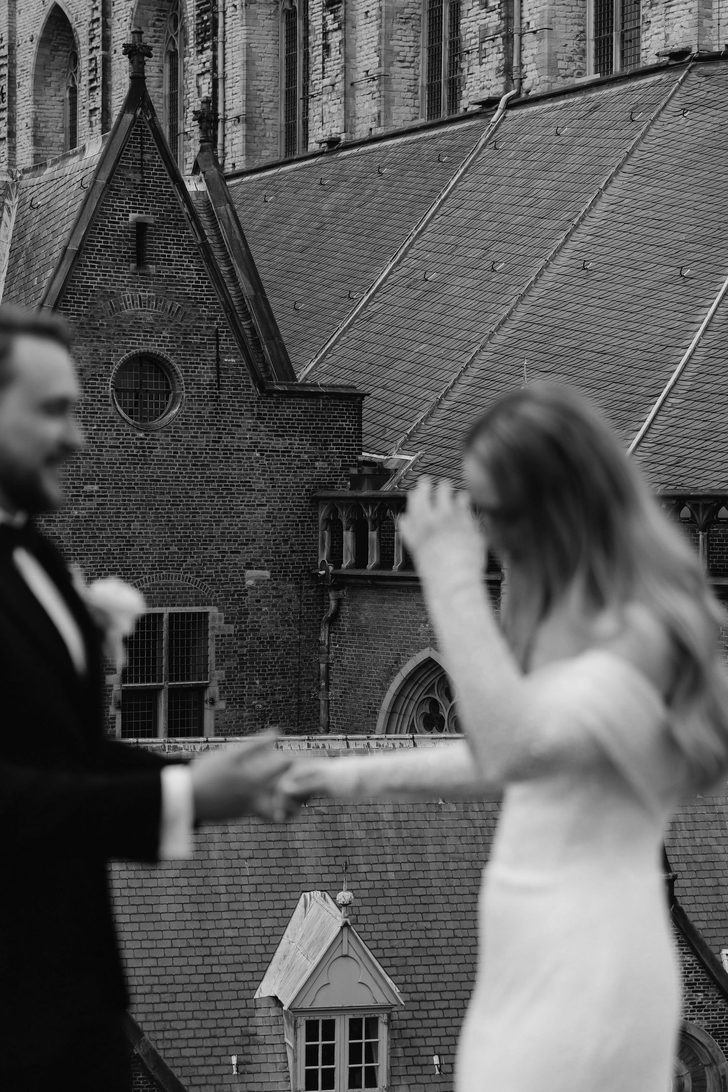 Couple dancing outside historic brick church building in wedding attire.