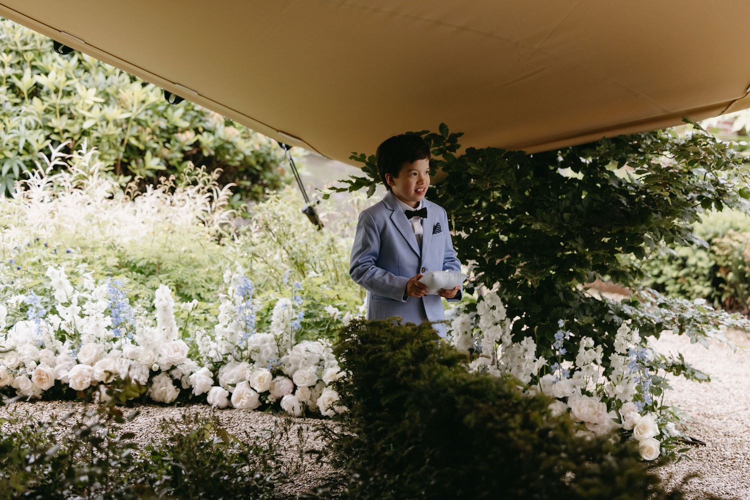 Wedding ceremony setup with elegant white floral arrangements under a covered outdoor venue.