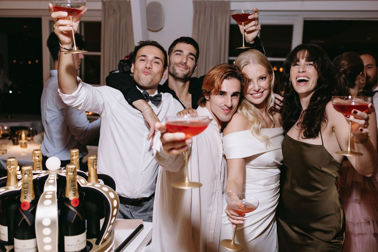 Group of wedding guests celebrating with cocktails and champagne at reception.