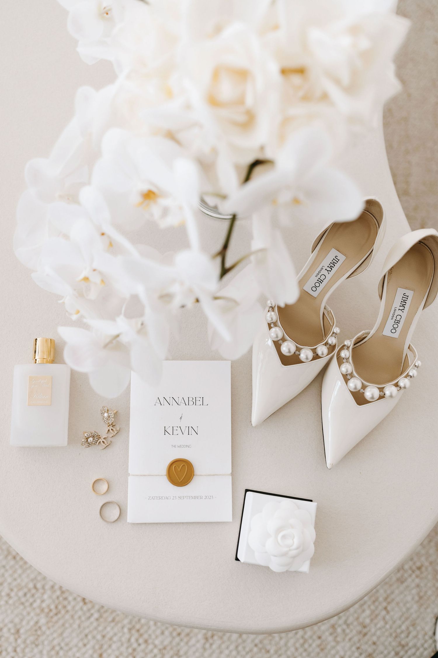 Elegant wedding flatlay with white shoes, invitation, and floral details.