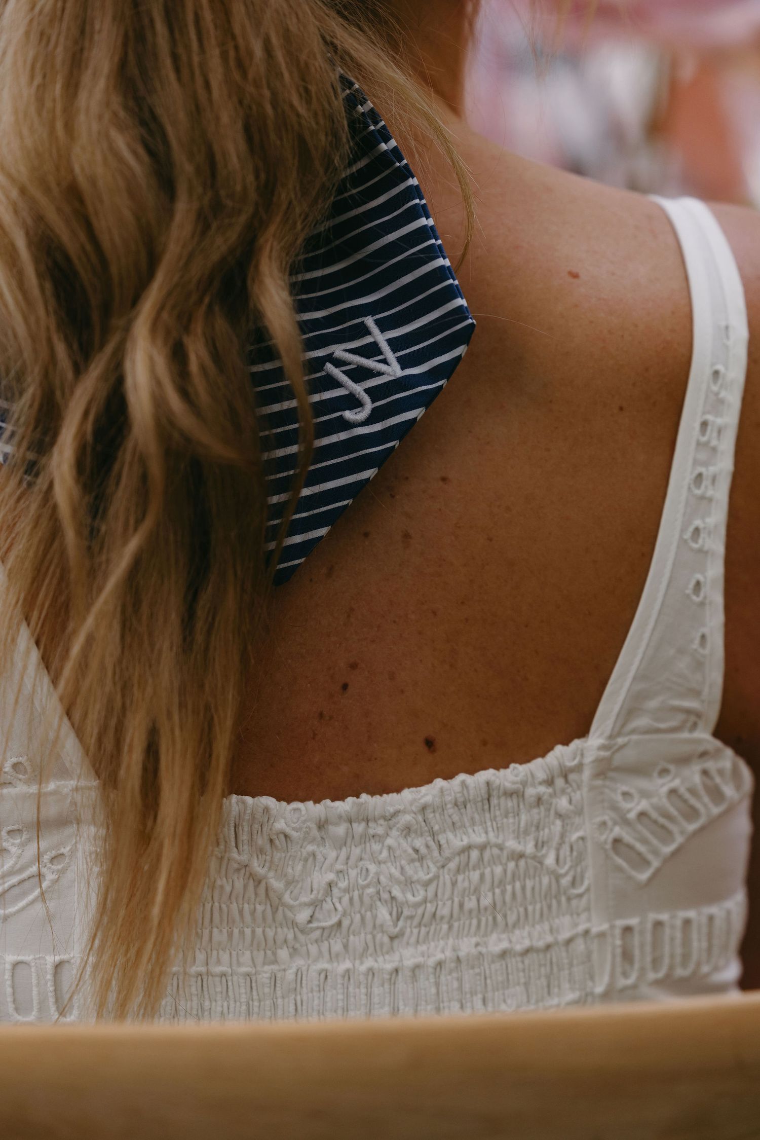 Close-up detail of a white wedding dress with delicate lace trim and striped fabric accent.