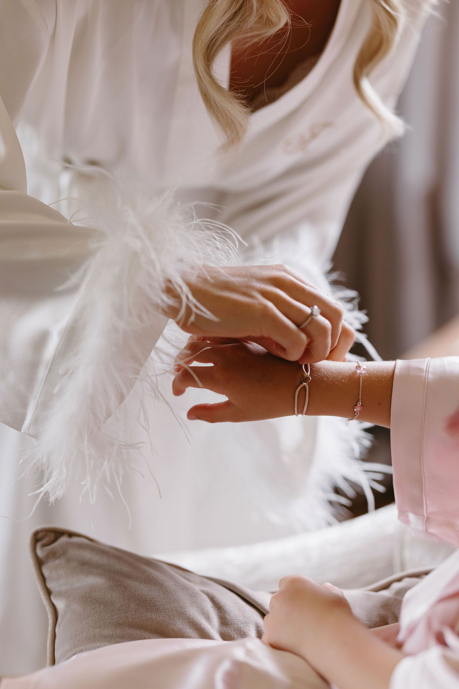 Close-up of delicate white feather details and jewelry on wedding attire.