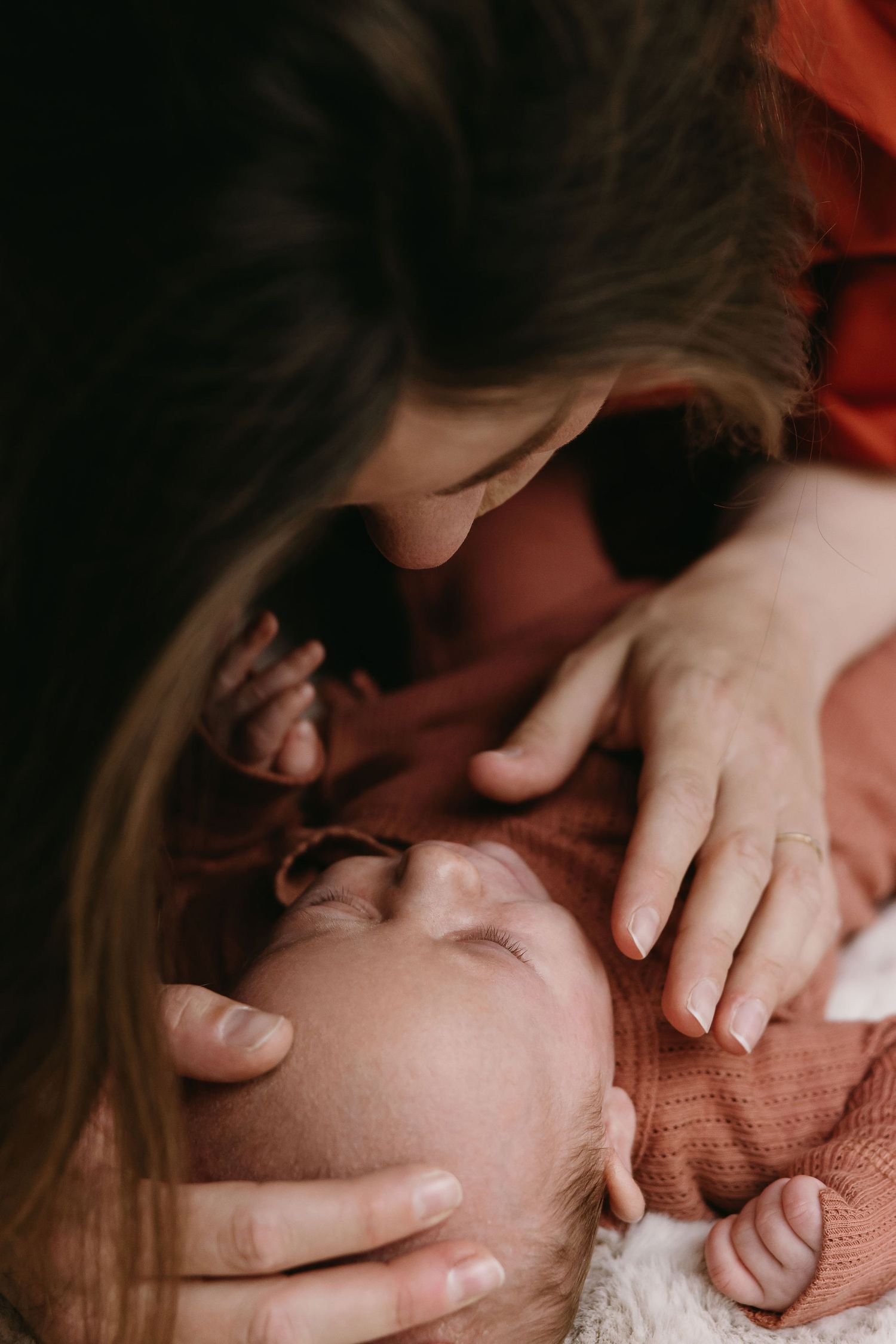 Intimate close-up series showing tender moments between parent and newborn baby in soft, warm lighting.