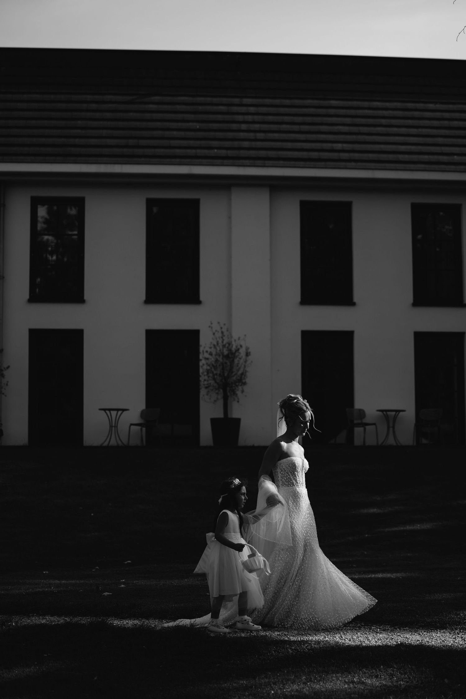 Artistic black and white shots of a bride in a wedding dress seated on the ground against a building.