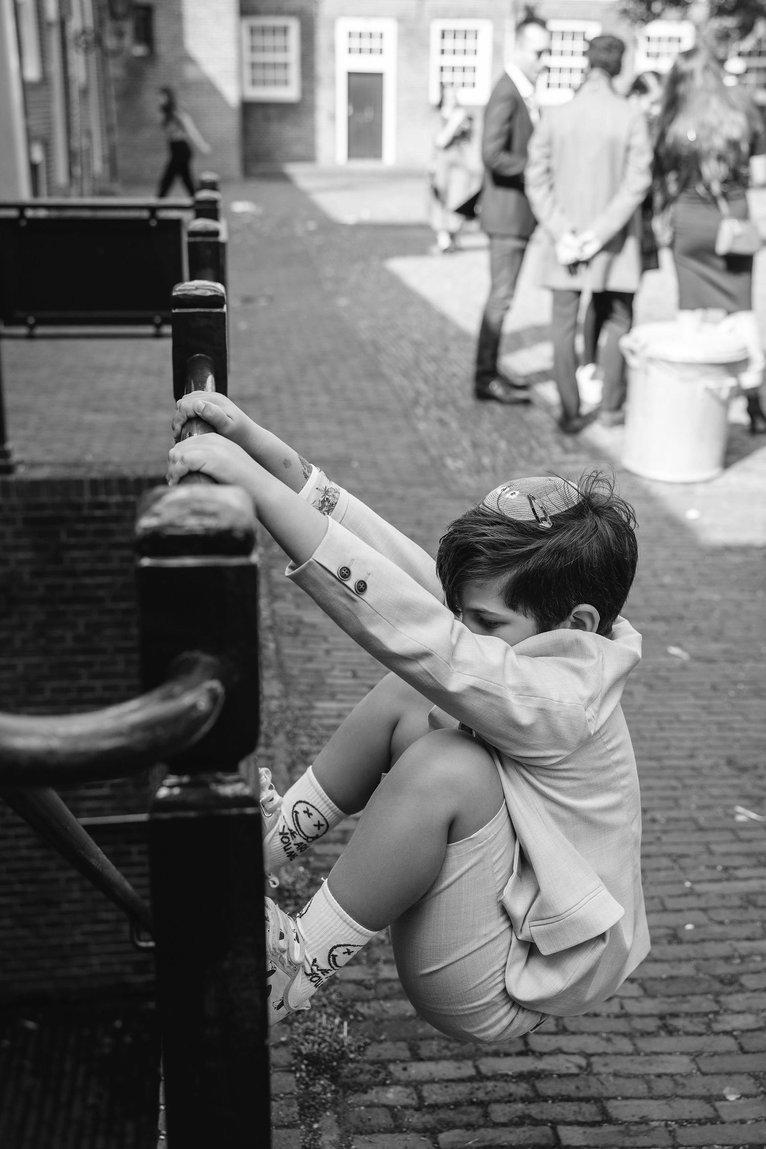 A young child in formal wear plays on outdoor steps at a wedding venue.