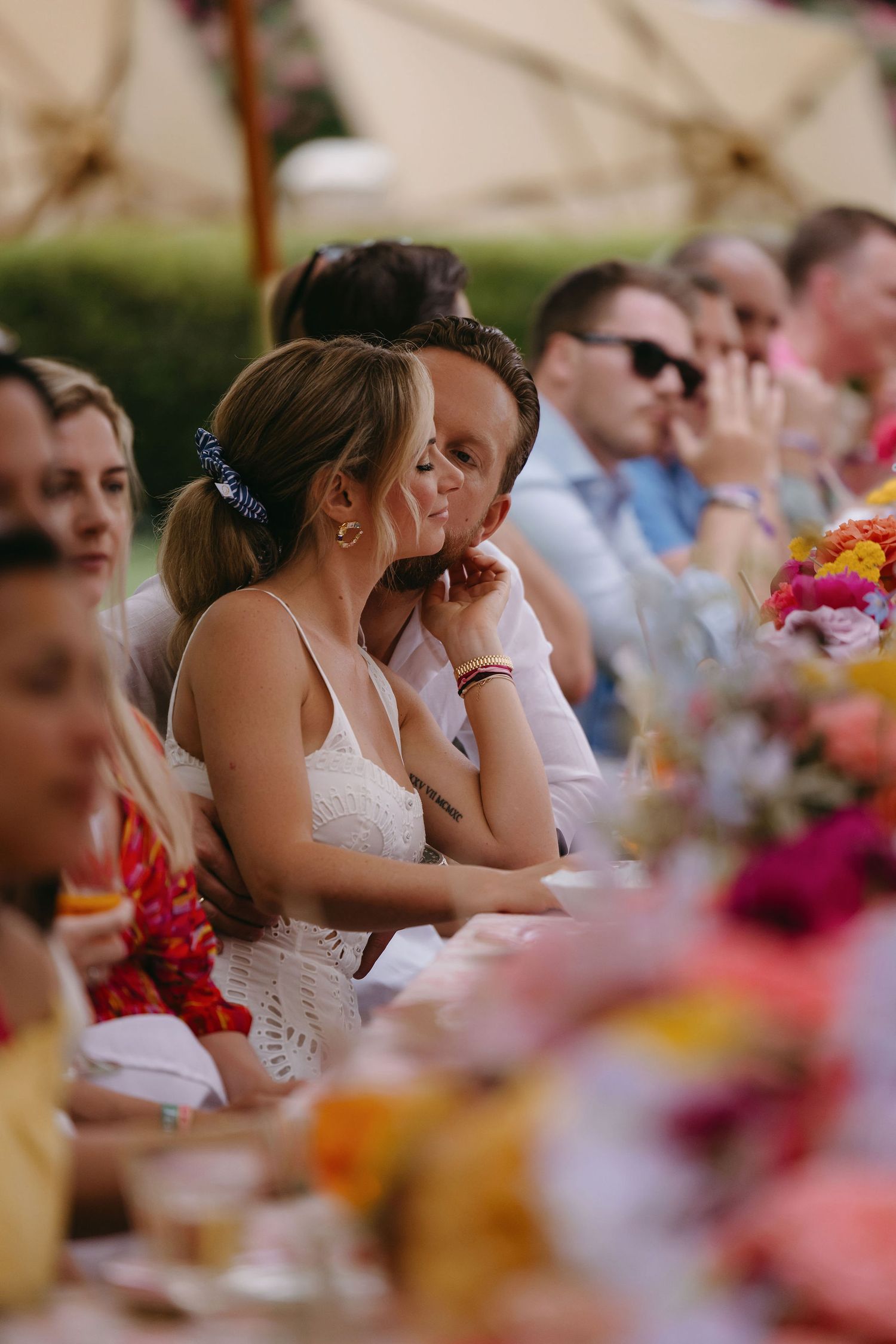 Wedding guests share moments of joy during an outdoor reception with colorful floral table decorations.