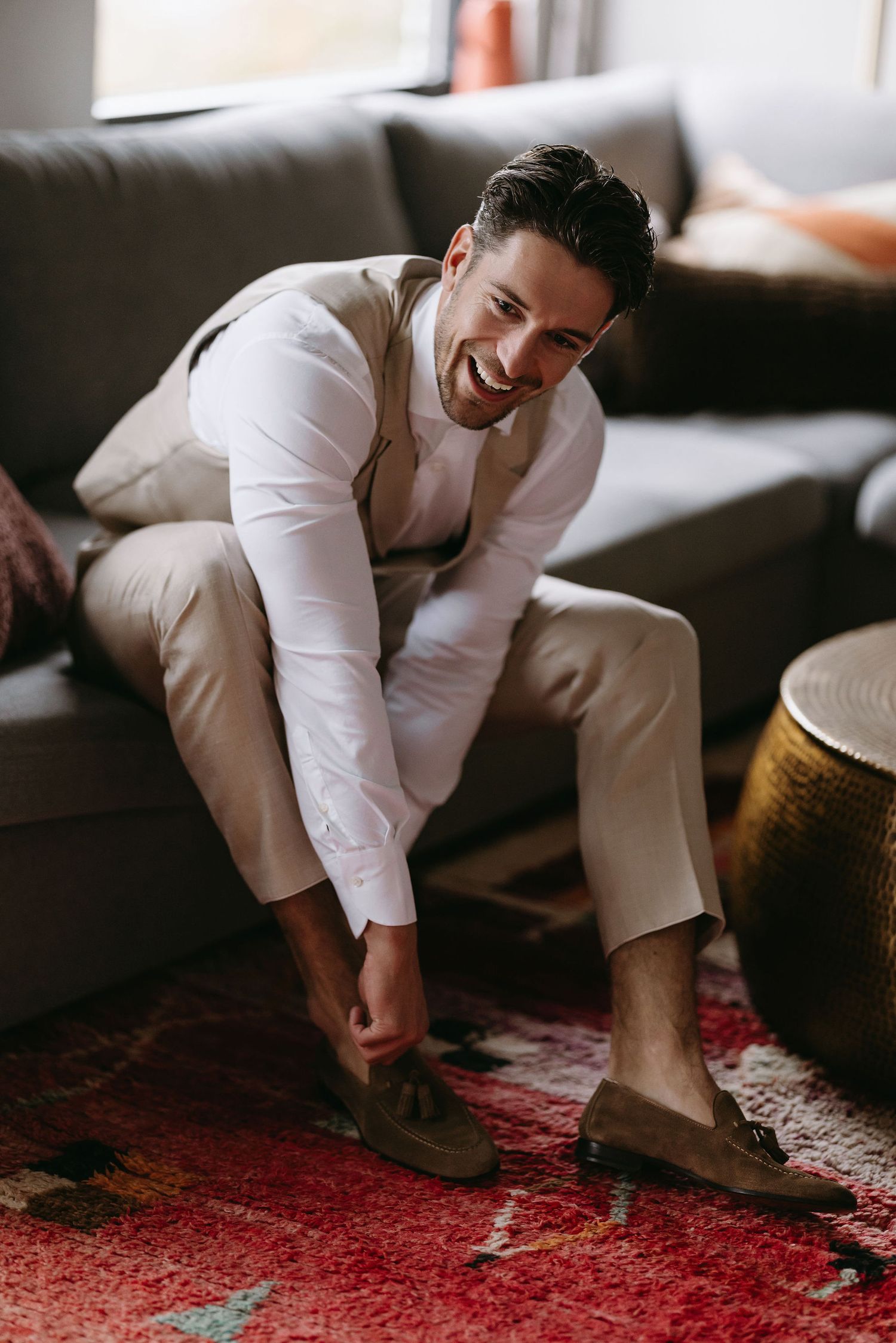 Candid moment of person in white attire putting on shoes while sitting on couch.