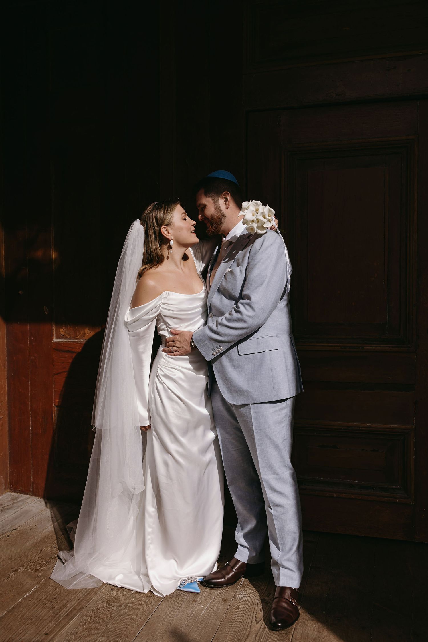 A romantic moment between newlyweds as they share an intimate embrace in a dimly lit venue.