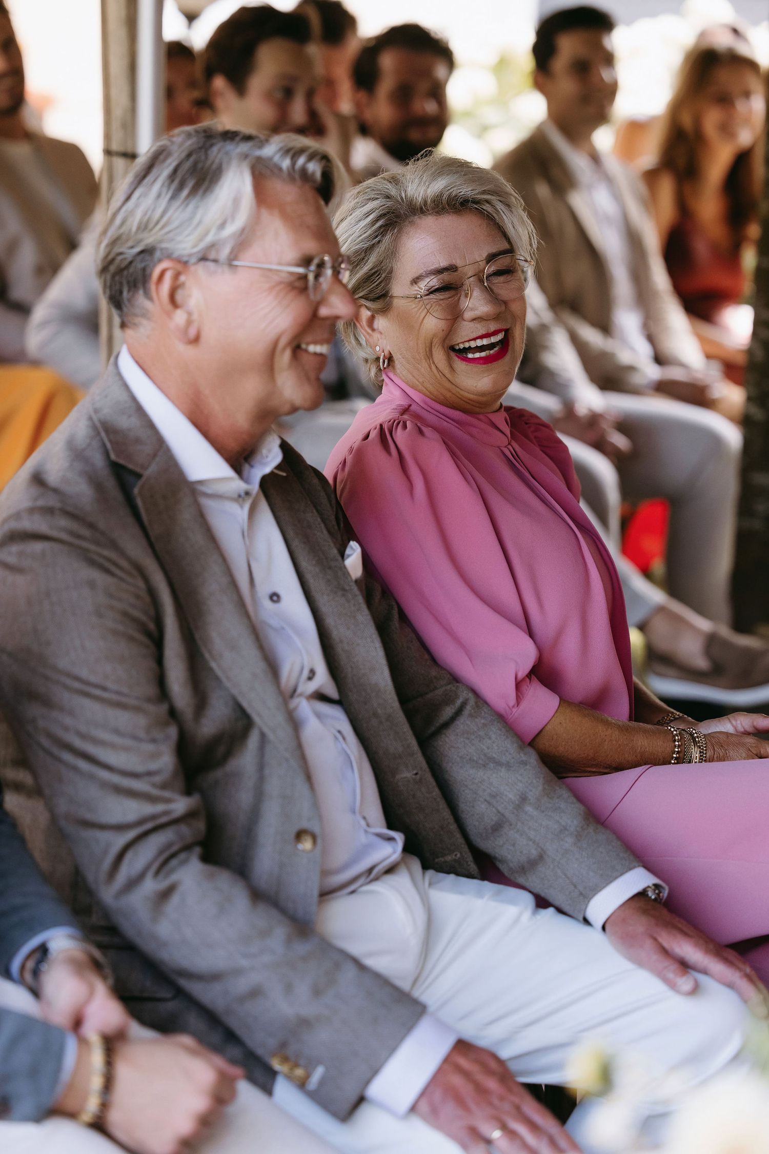 Wedding guests enjoying a light moment during the ceremony.