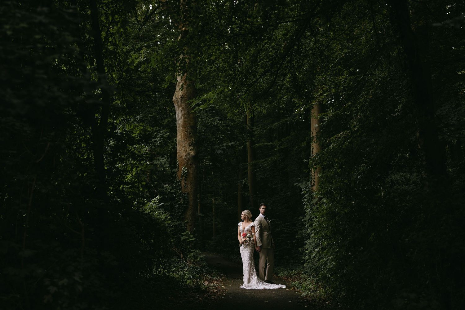 A wedding ceremony takes place in a serene forest setting with tall trees.