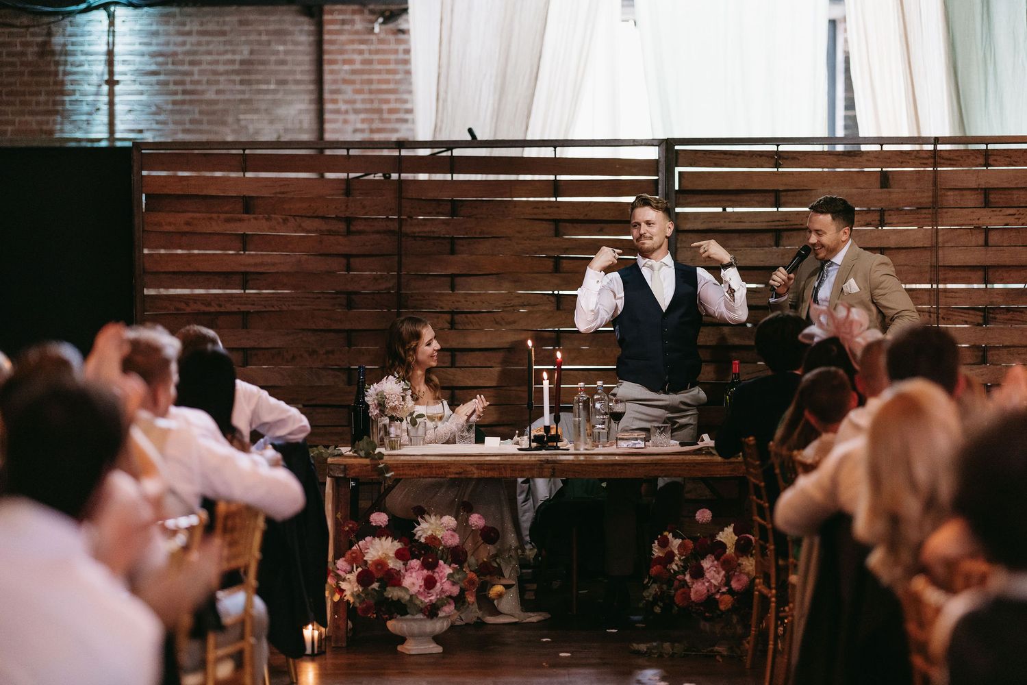 Guests enjoying a lively celebration at a rustic indoor wedding reception venue with wooden decor.