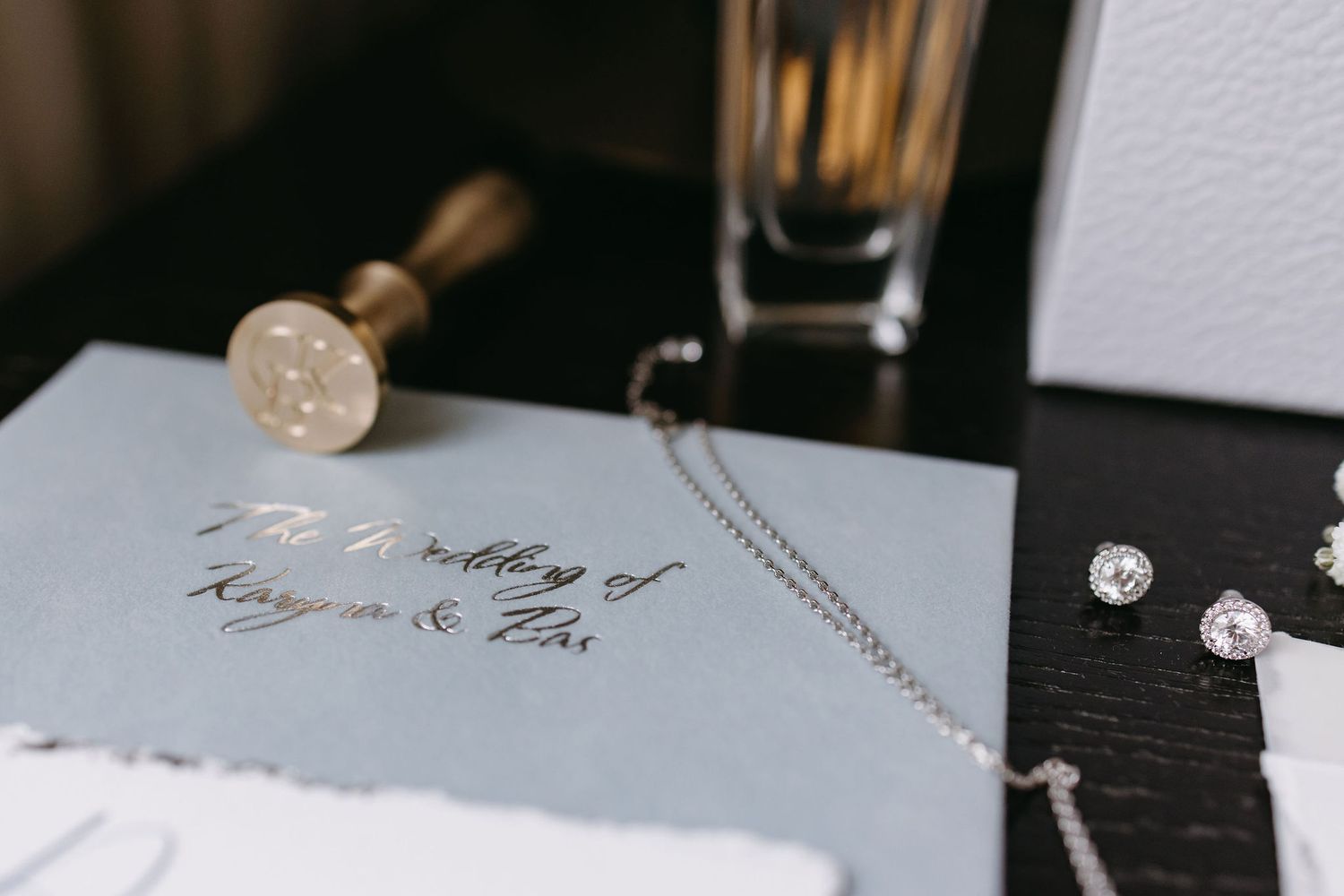 Wedding details including calligraphy invitations and delicate accessories on white surface.