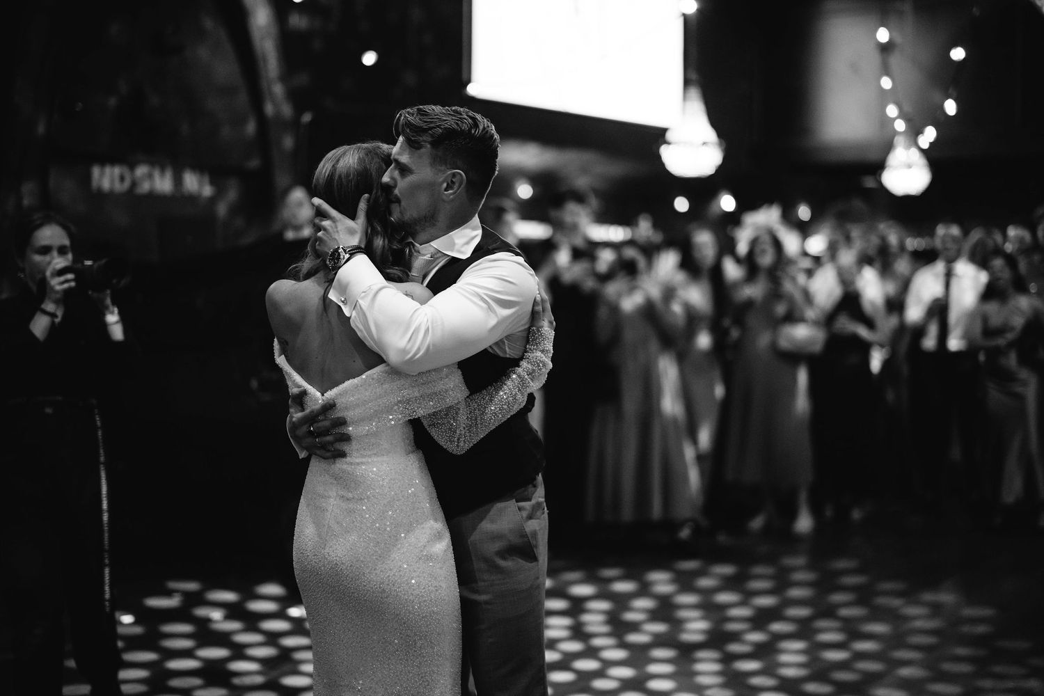Reception venue with dancing couples silhouetted against dark atmospheric lighting.