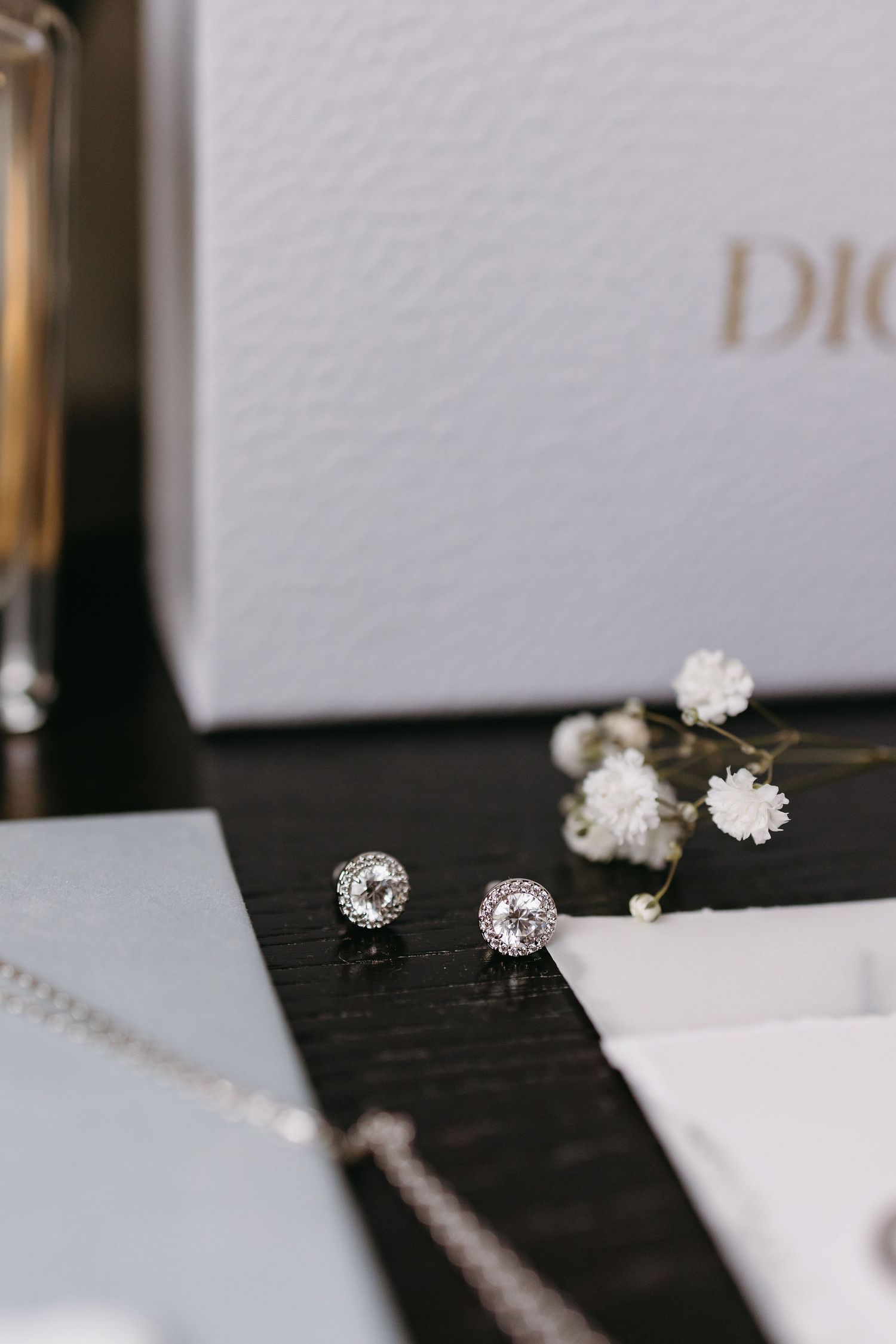 Elegant wedding jewelry details featuring diamond stud earrings and delicate white flowers.