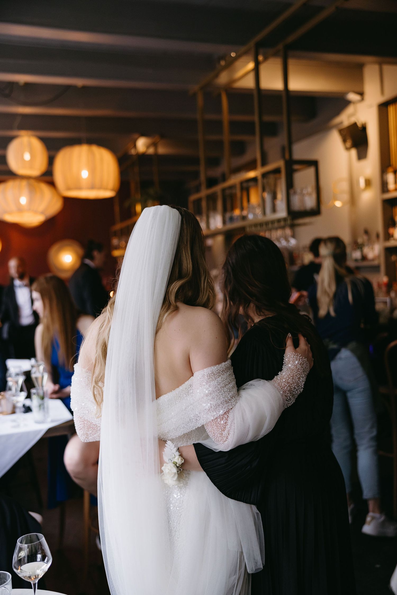 Wedding reception scene with guests dancing under pendant lights in dimly lit venue.