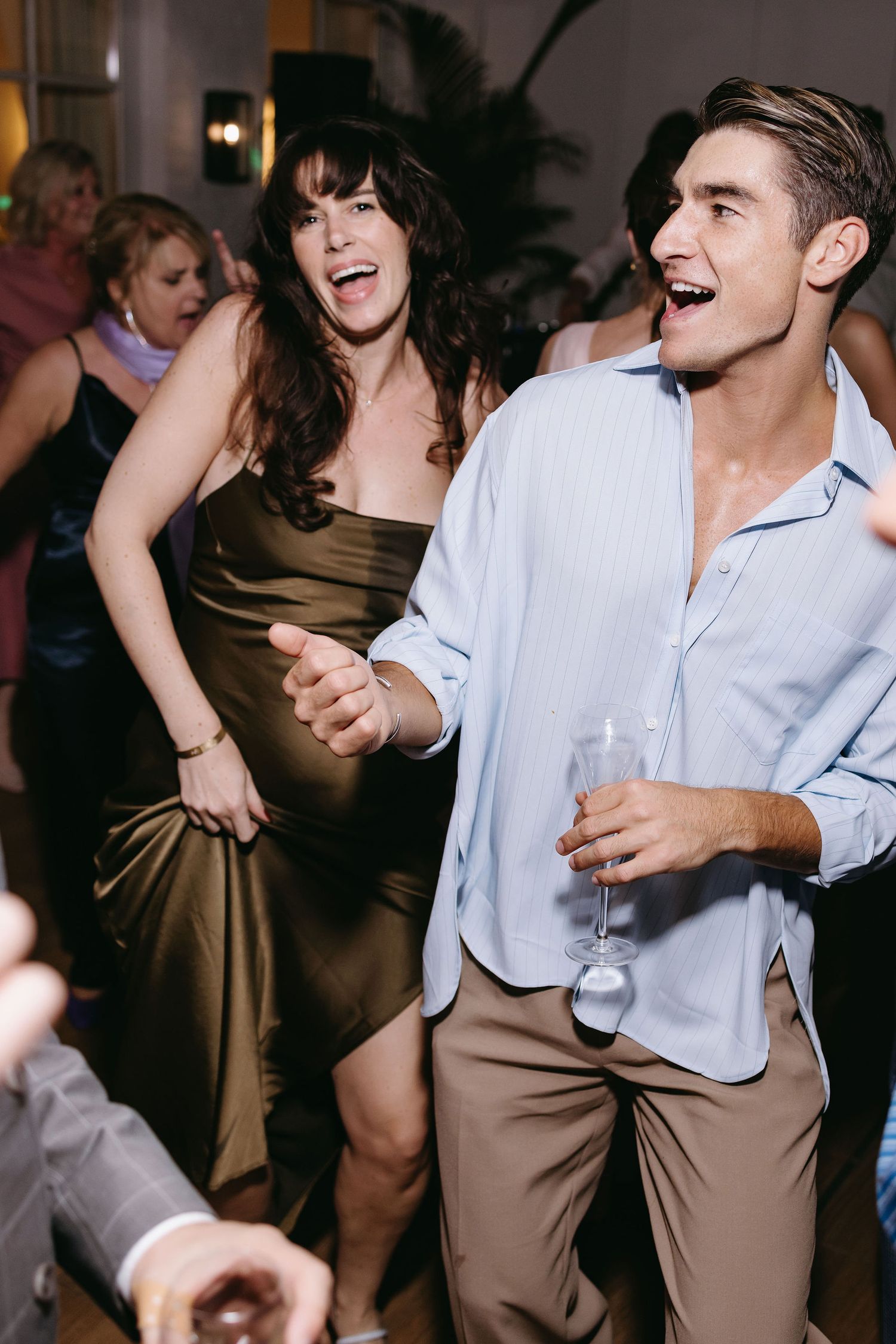 Wedding guests dancing and laughing at reception party.