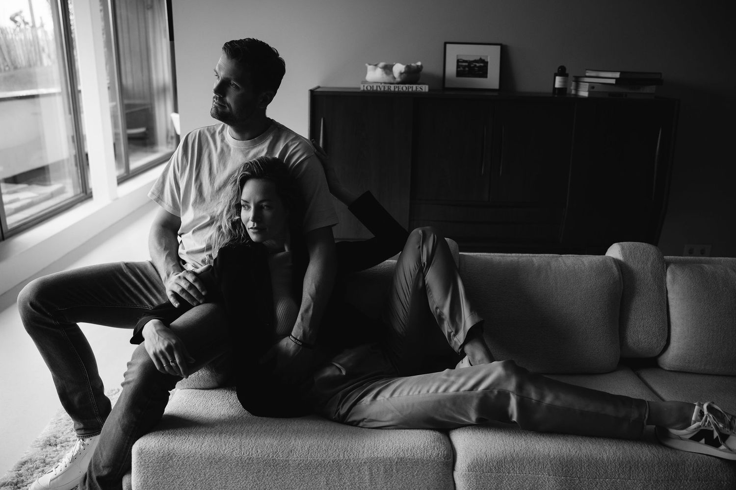 A series of silhouetted figures relaxing together on a couch in moody lighting.