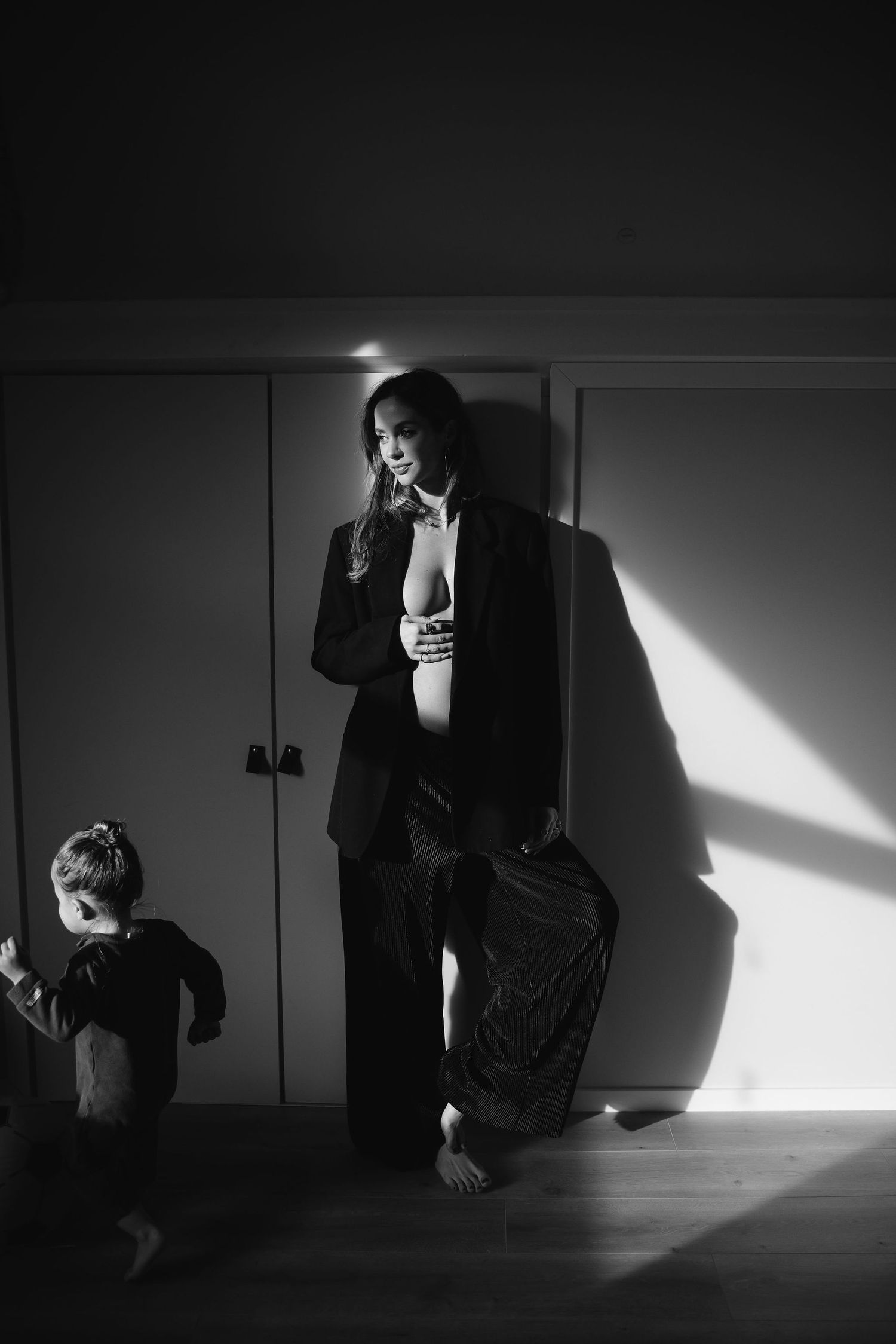 A dramatic black and white photo with strong shadows showing figures in a minimalist interior.