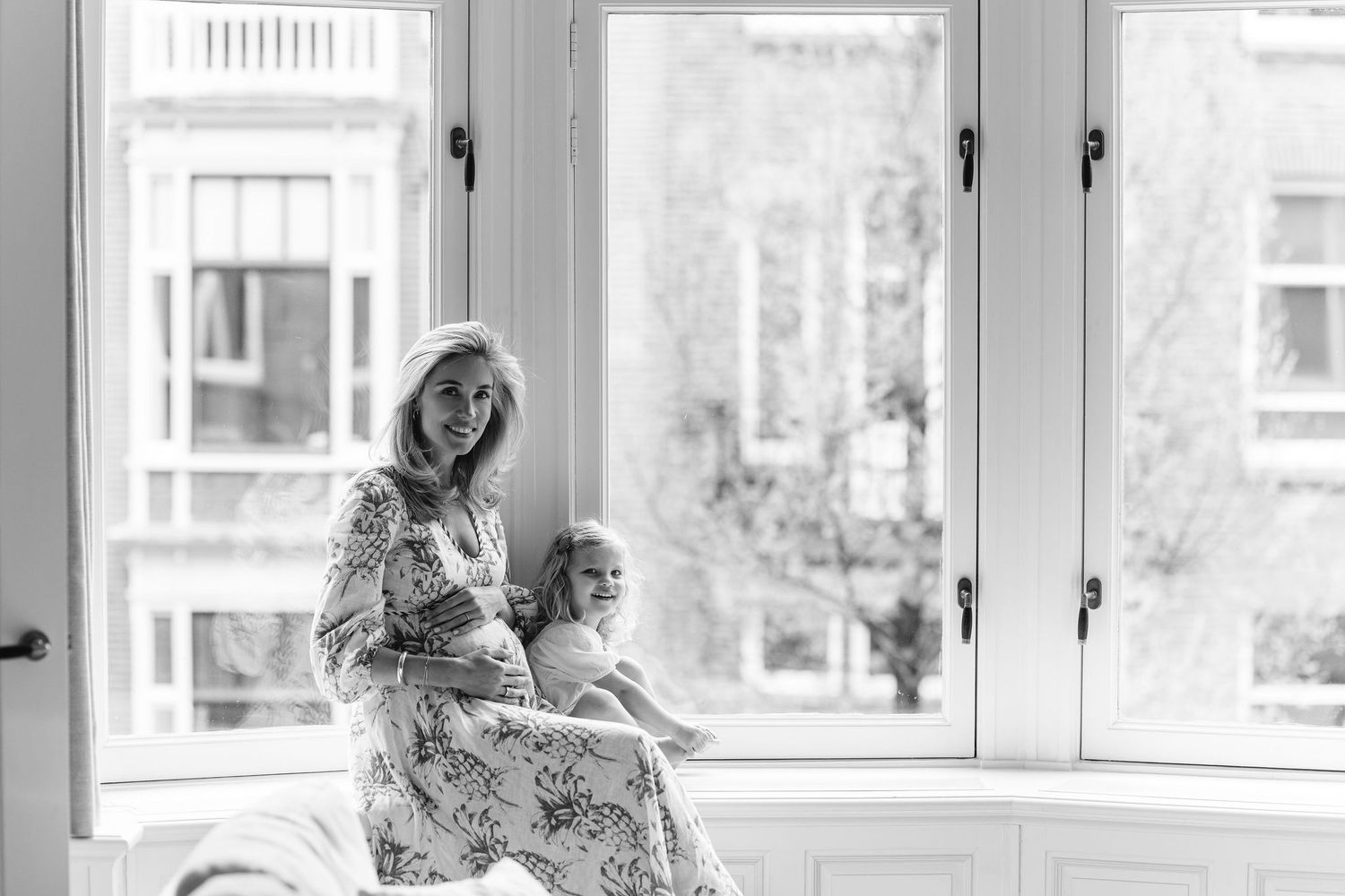 Black and white photo by window showing tender family moment.