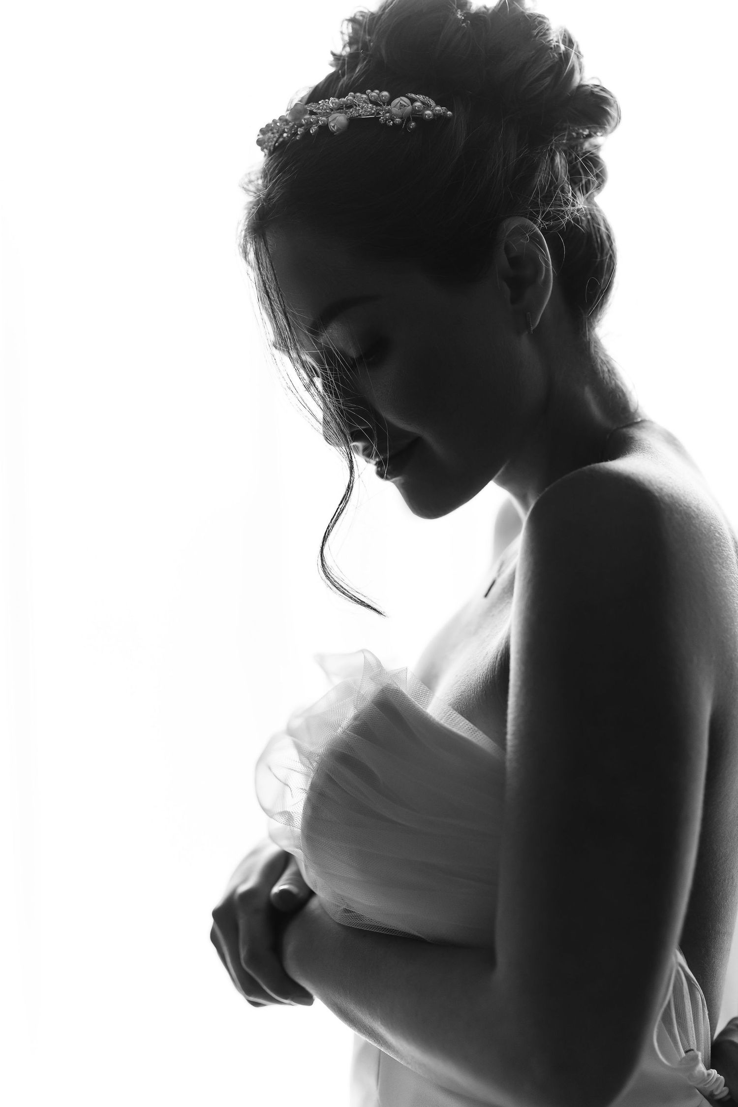 A silhouetted profile of a woman in a white dress gazes downward in a dramatic black and white portrait.
