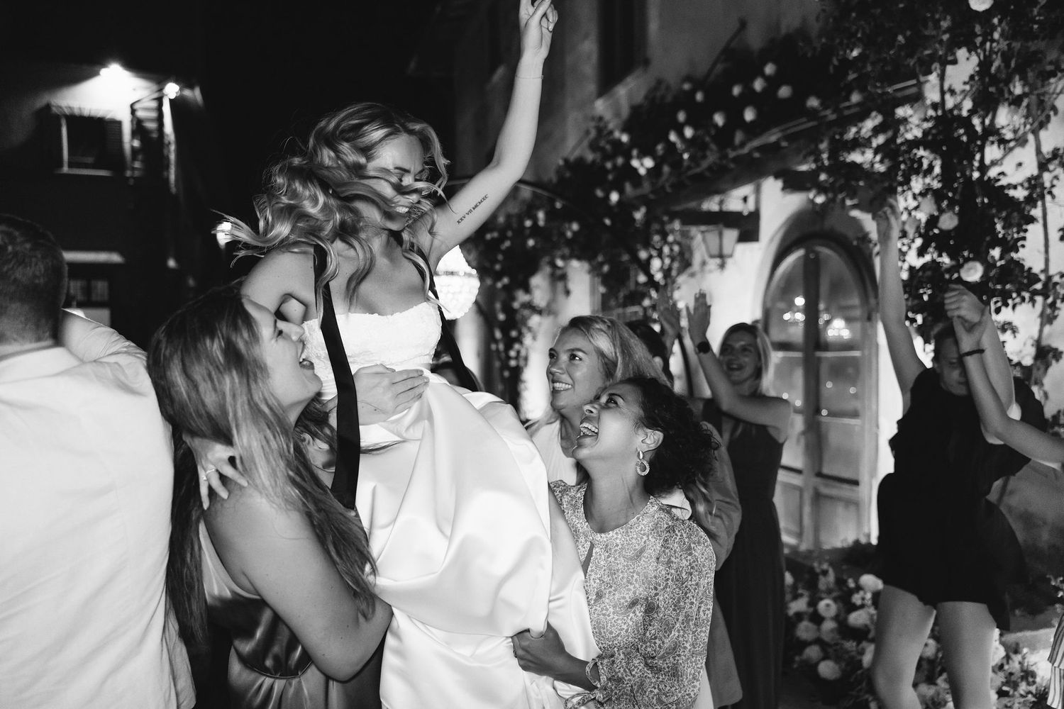 Black and white photo of people dancing and celebrating energetically at a wedding reception party.