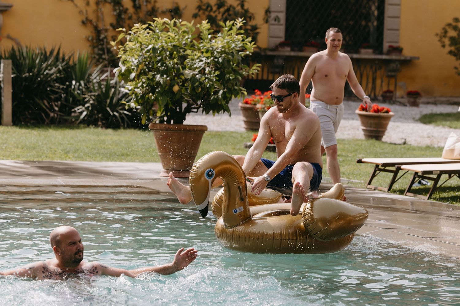 People enjoying a summer pool party with inflatable swan float.