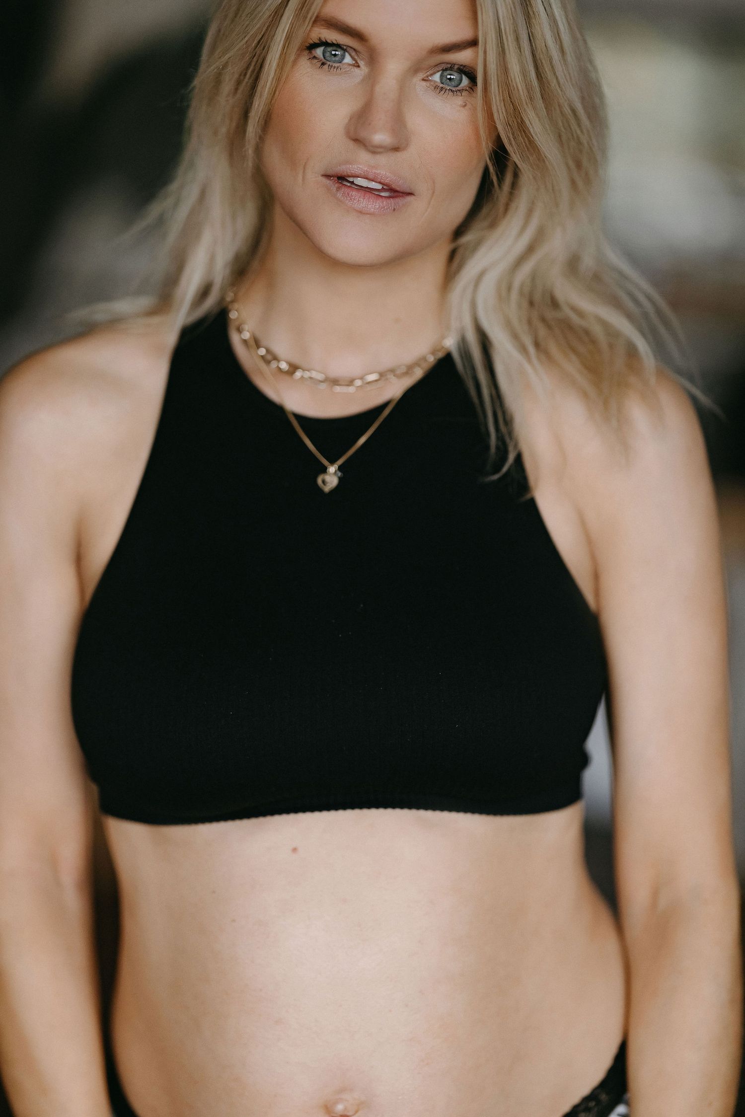 Close-up portrait wearing black crop top and layered necklaces.