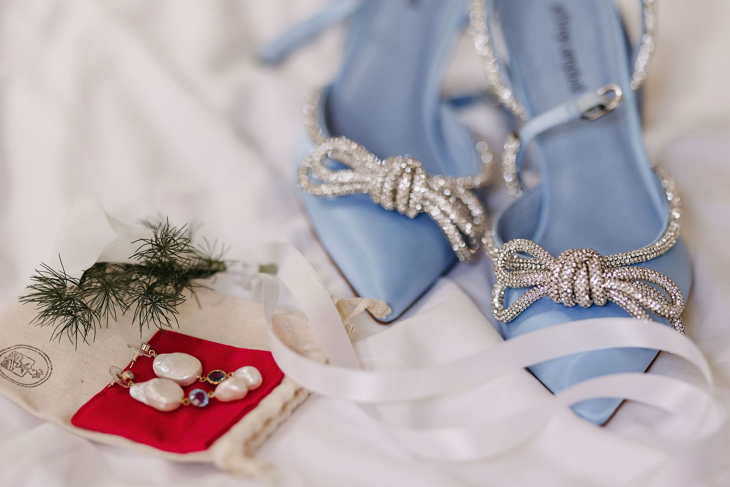 Sparkly bow-shaped accessories and buttons displayed on blue fabric with evergreen sprigs.