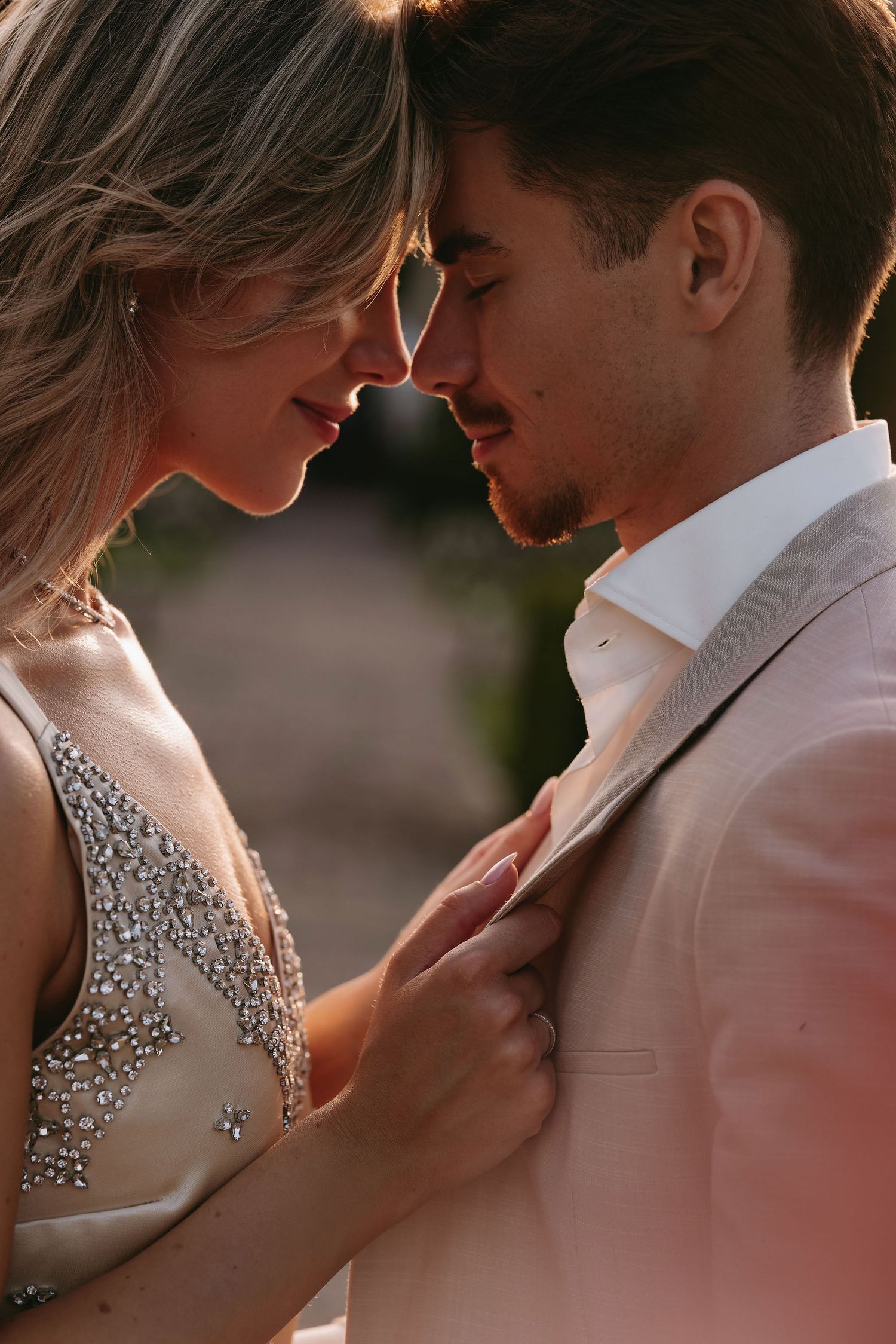 Romantic close-up of couple in formal wear sharing an intimate moment at sunset.