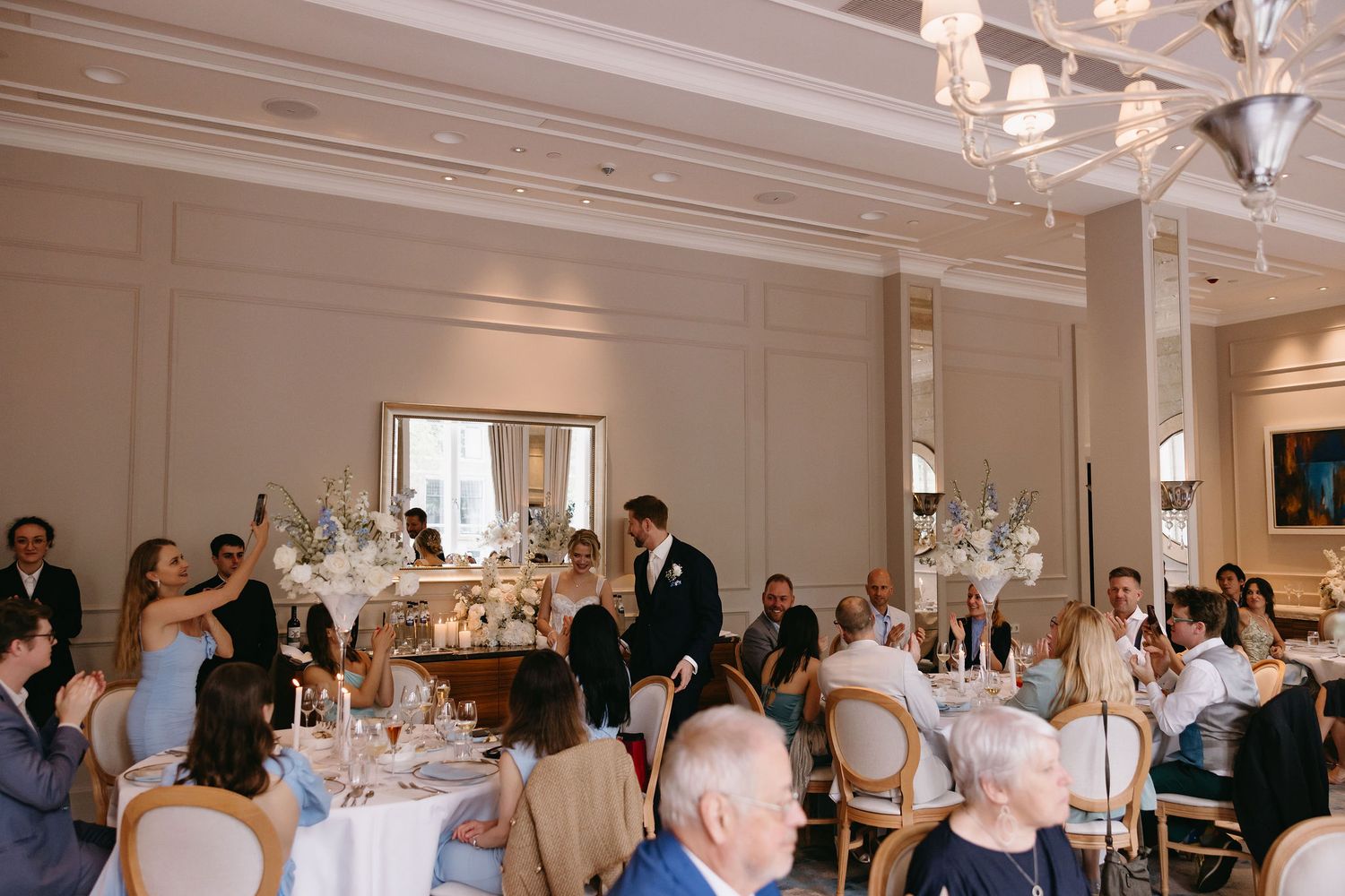 Elegant wedding reception hall decorated with crystal chandeliers and white table settings.
