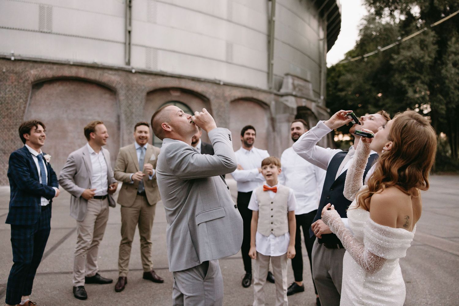Wedding party members in light colored attire pose together outdoors.