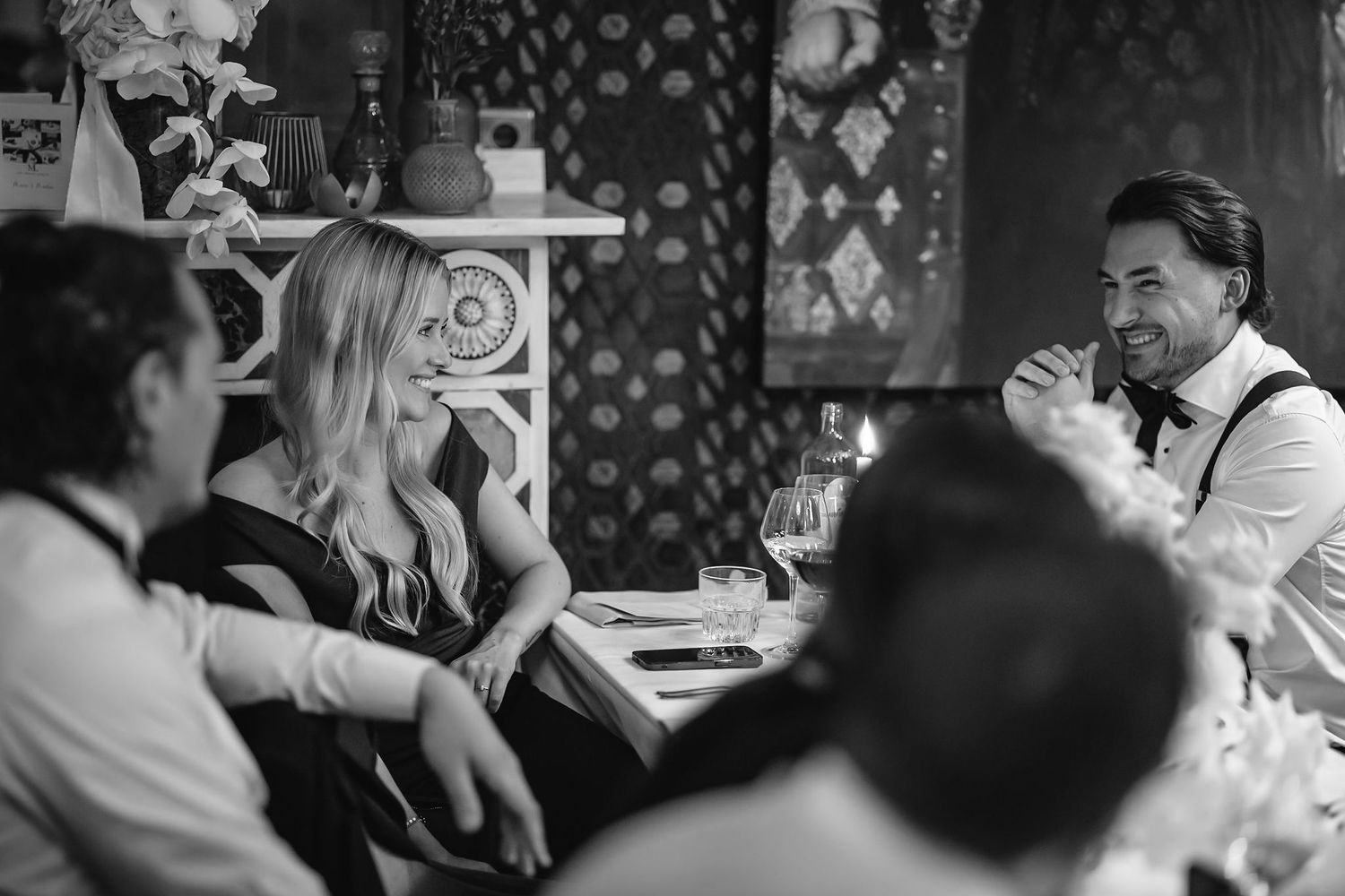 Guests enjoying an intimate conversation at an elegant dinner party in black and white.
