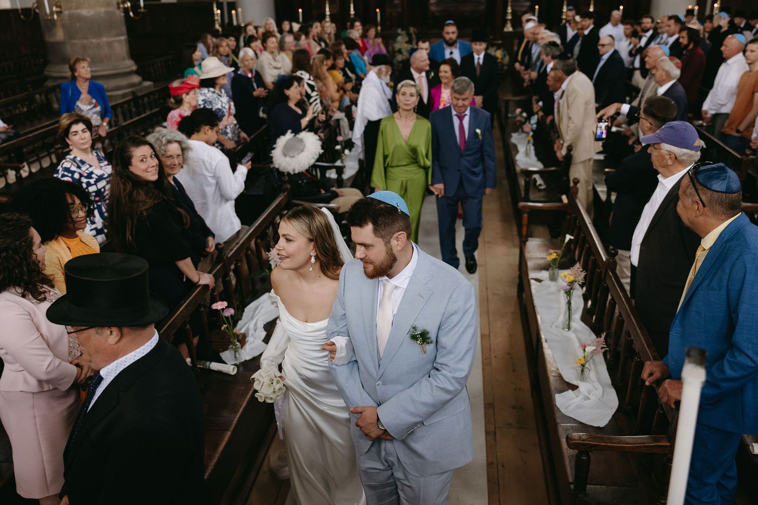 Large crowd gathered in formal attire at an indoor wedding celebration.