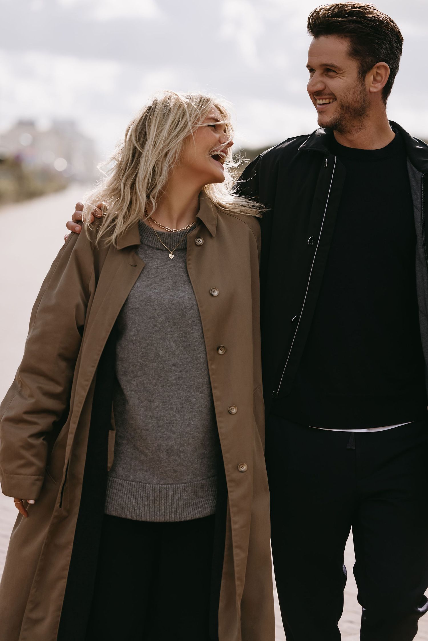 Couple shares intimate moment outdoors wearing neutral winter clothing.