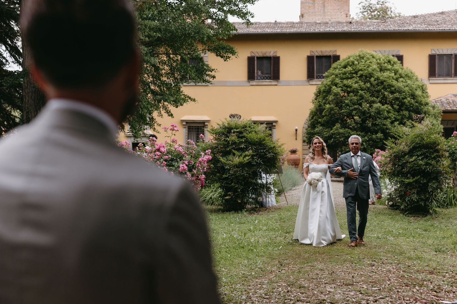 Wedding procession through garden pathway at Italian villa venue.