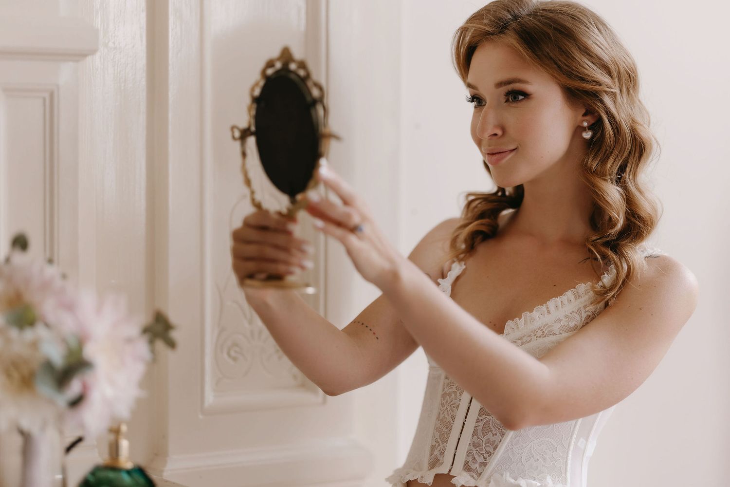 Elegant bridal preparation photos in a bright white room with mirrors.