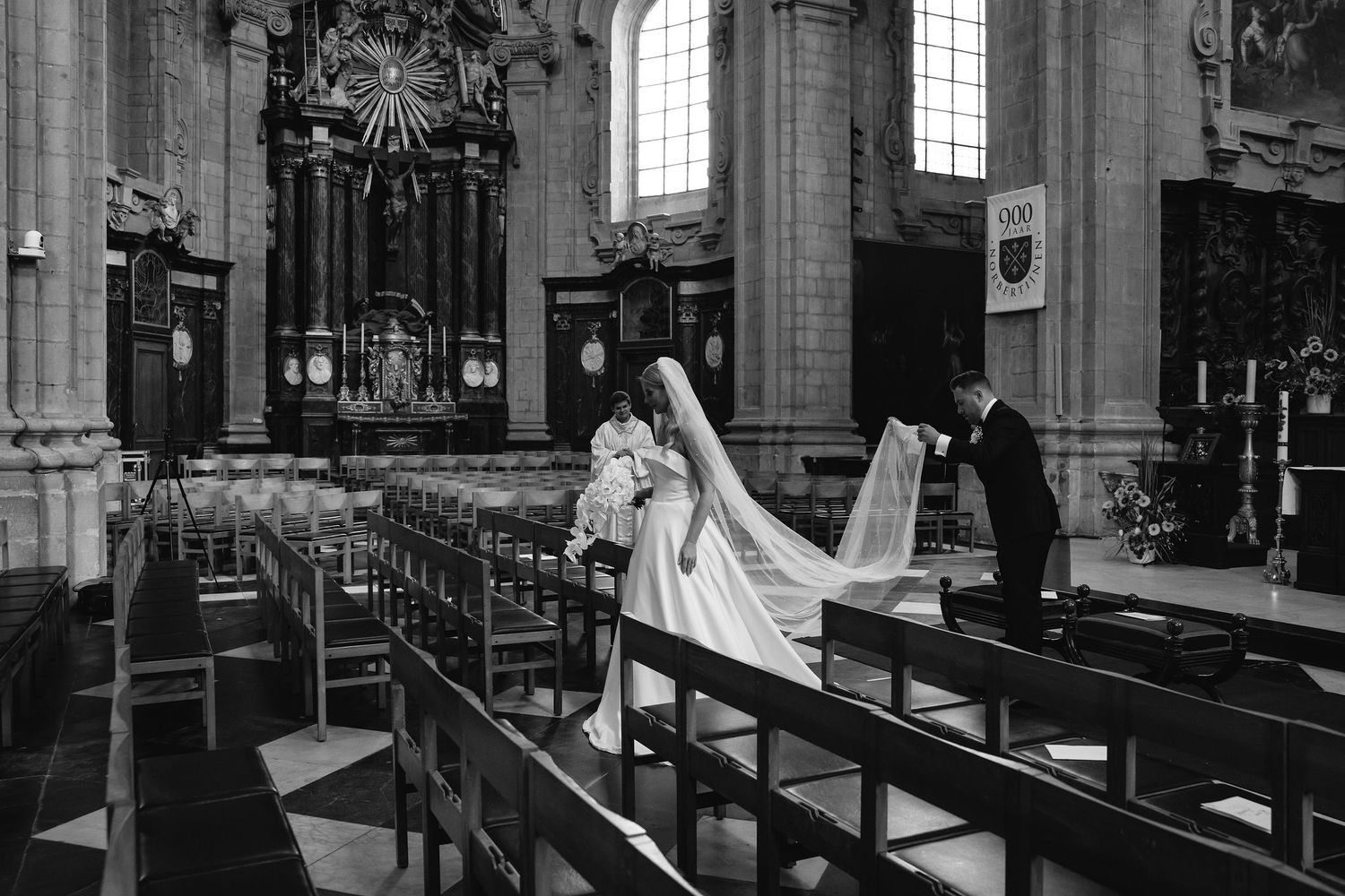 Black and white photo of wedding ceremony in historic church with dramatic architectural details.