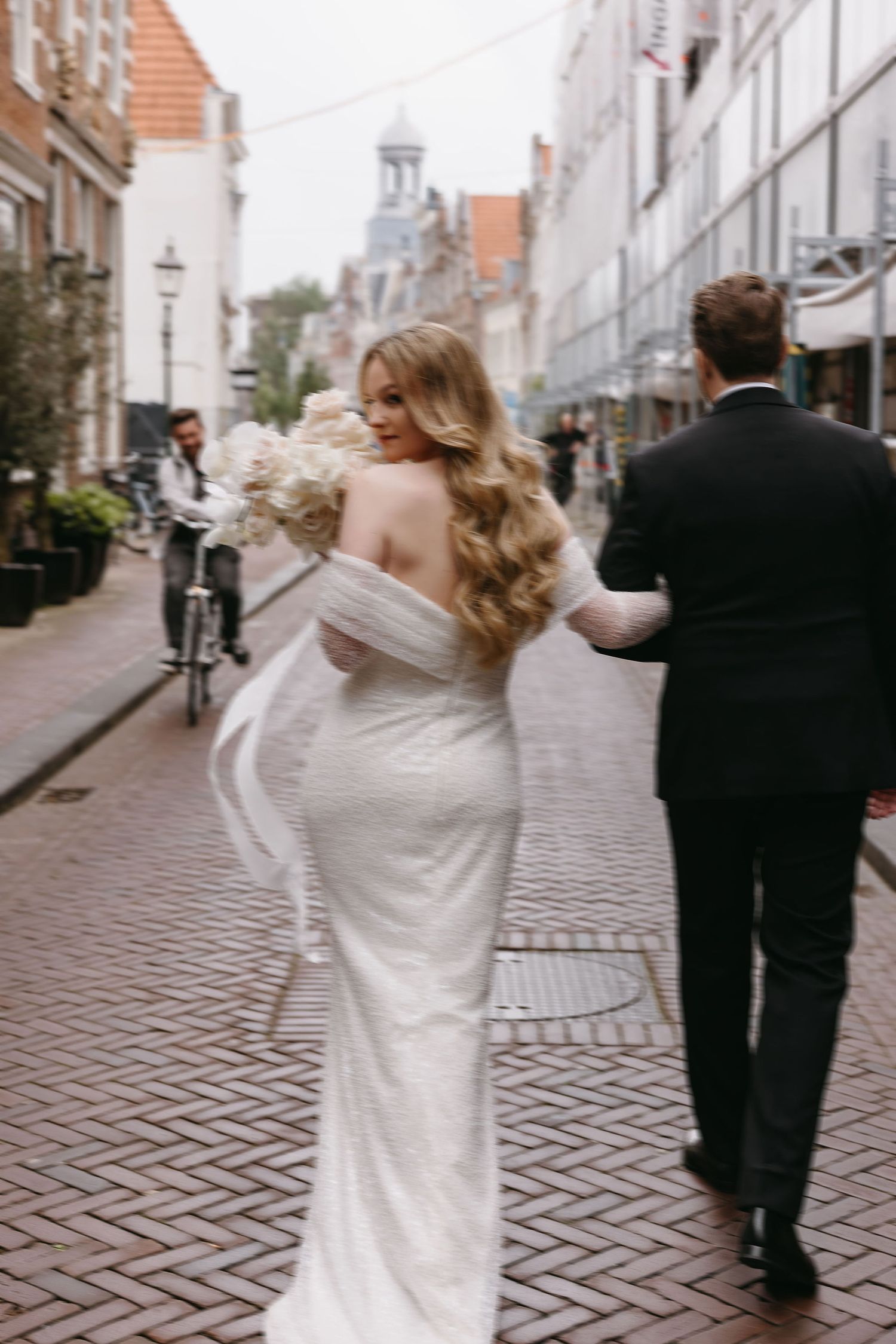 Couple walking down a charming European cobblestone street after their wedding ceremony.