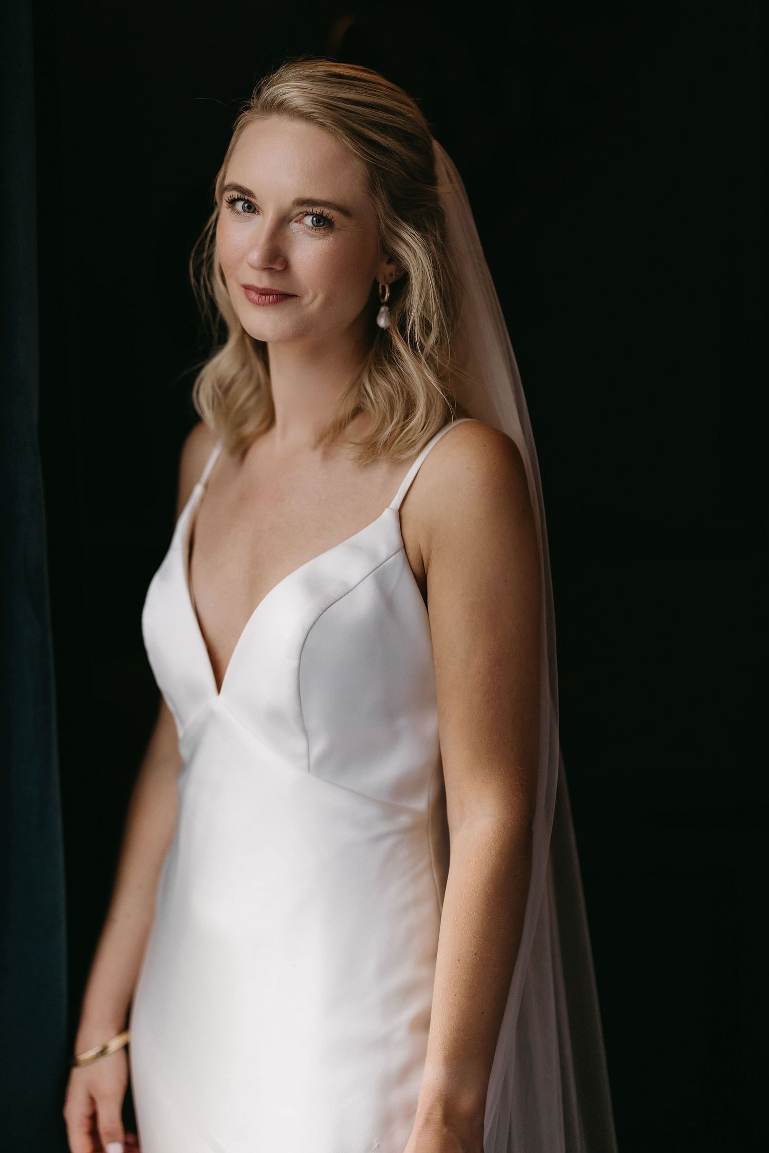 Portraits showing details of a sleek white wedding dress with a v-neckline.